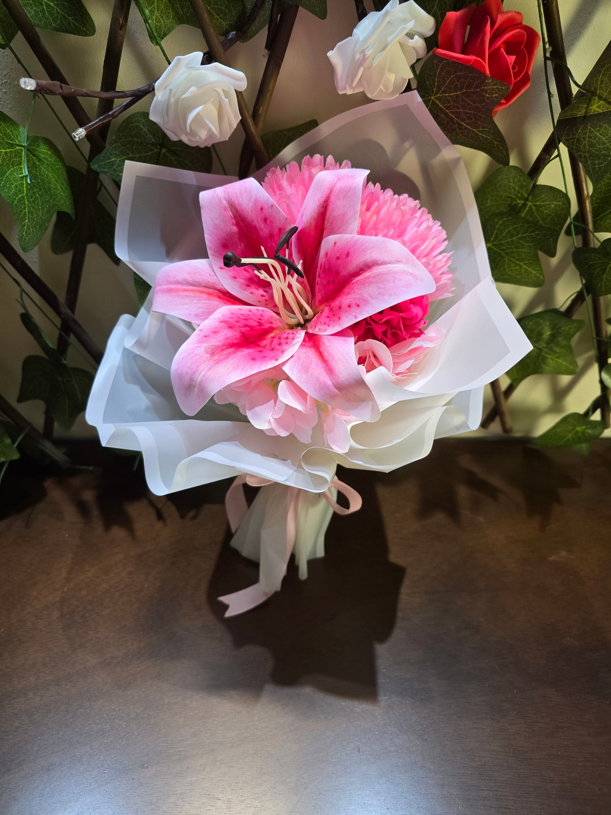 BioCode artificial pink lily and hydrangea bouquet wrapped in white paper with a soft pink satin ribbon.