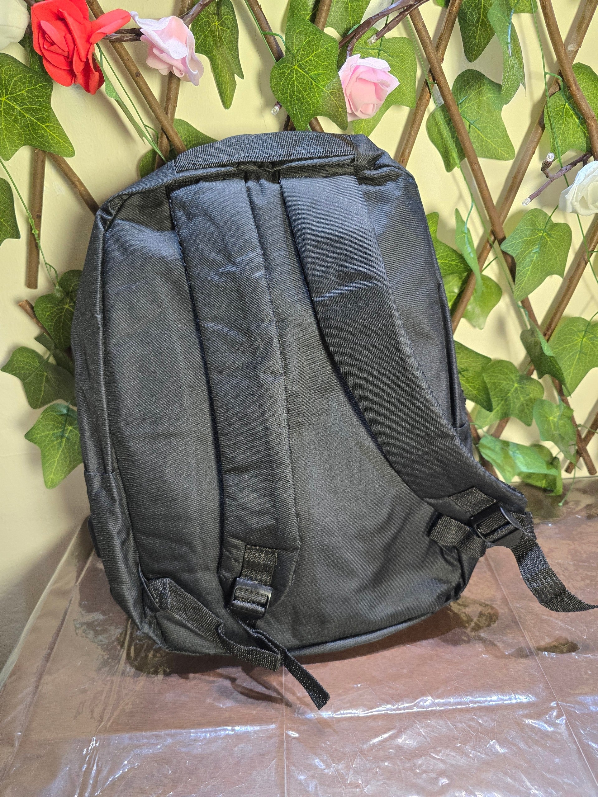 BioCode black minimalist laptop backpack with padded adjustable shoulder straps against a decorative floral background