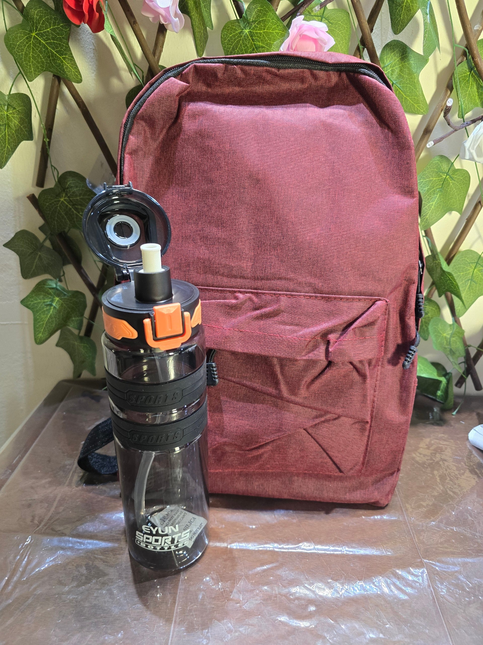 BioCode burgundy textured backpack and clear sports water bottle with black and orange flip-top lid and straw