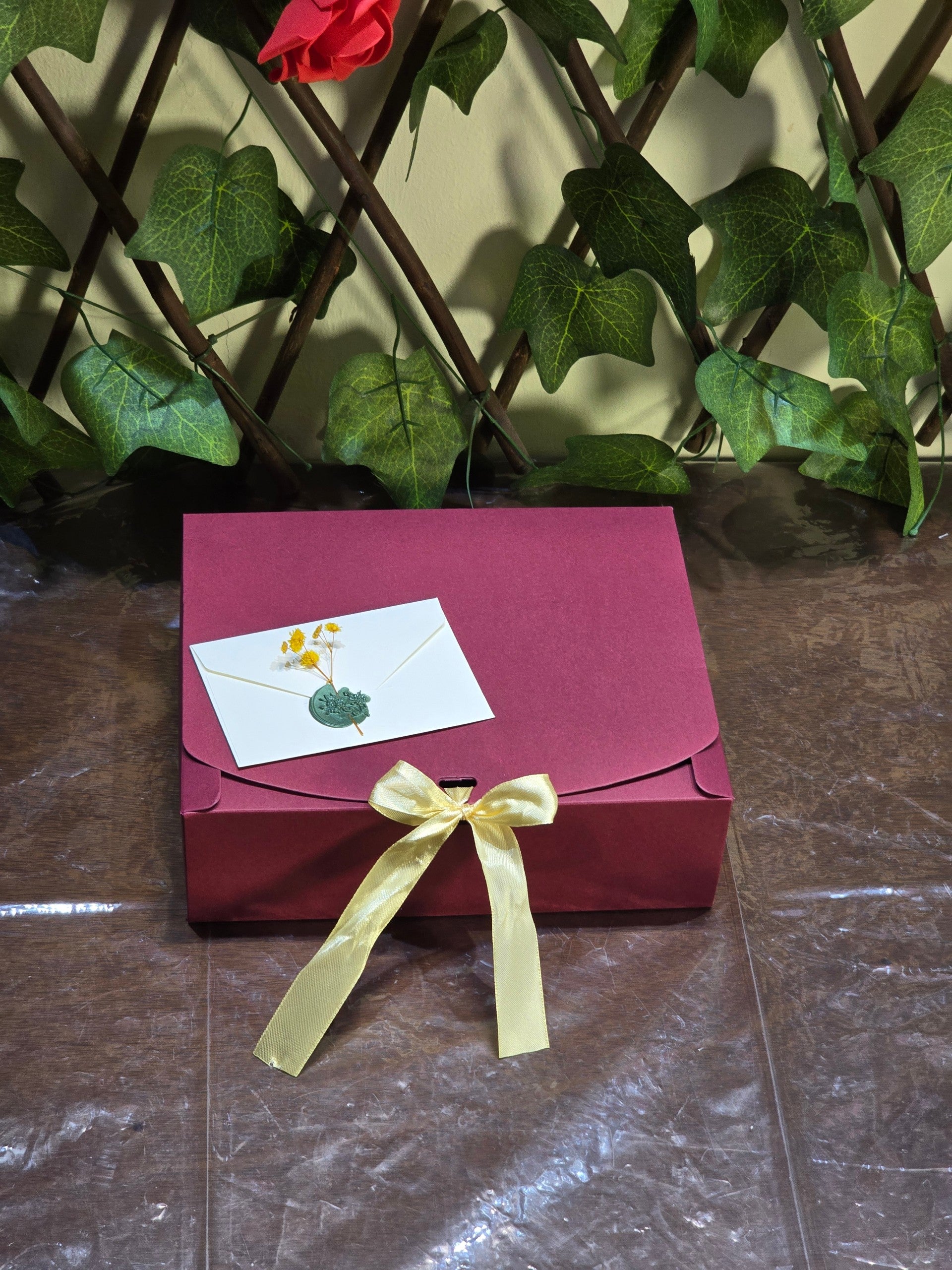 BioCode deluxe beauty gift set in a deep burgundy box with a gold ribbon and wax-sealed note against a leafy backdrop