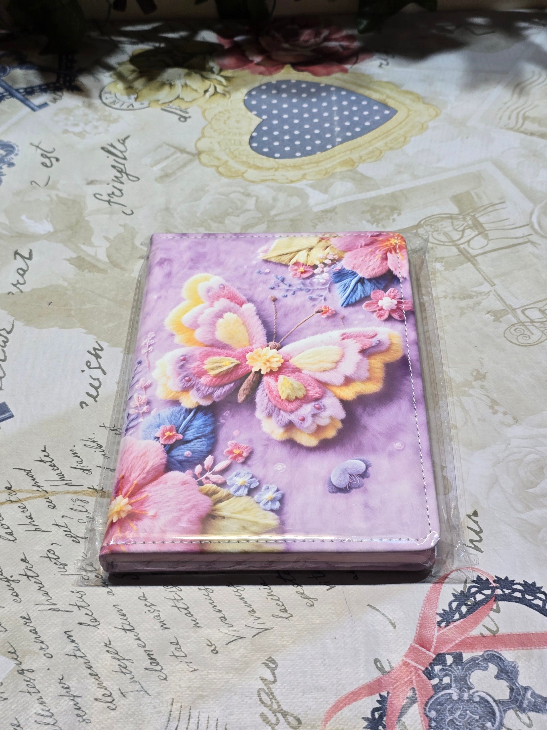 BioCode butterfly and floral print notebook with a soft purple textured cover on a vintage-style patterned surface