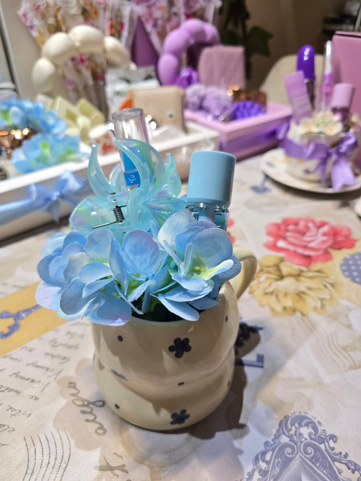 BioCode decorative cream ceramic mug filled with blue silk hydrangeas, a flower hair clip, and blue beauty essentials.