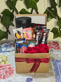BioCode coffee and chocolate gift hamper in a kraft box with a red ribbon, travel mug, coffee sachets, and roses.