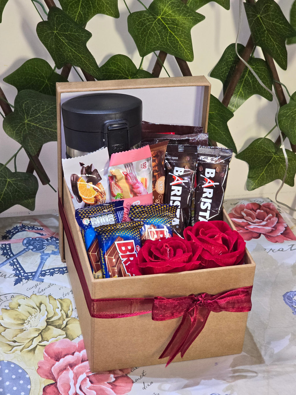 BioCode coffee and chocolate gift hamper in a kraft box with a travel mug, coffee sachets, chocolates, and red roses.