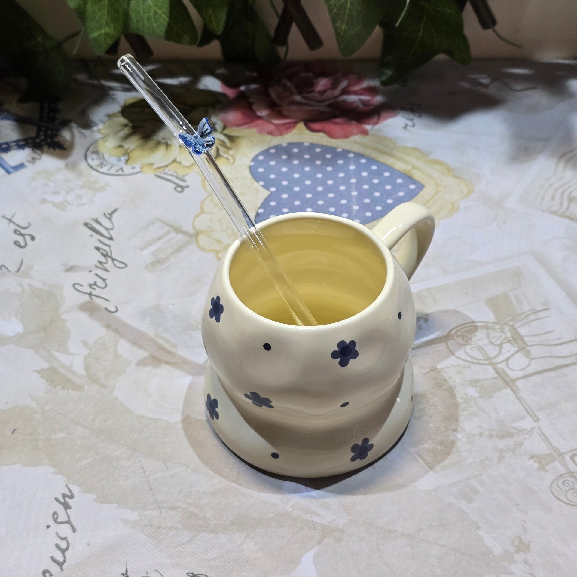 BioCode cream ceramic mug with blue floral accents and a clear glass straw featuring a delicate butterfly detail