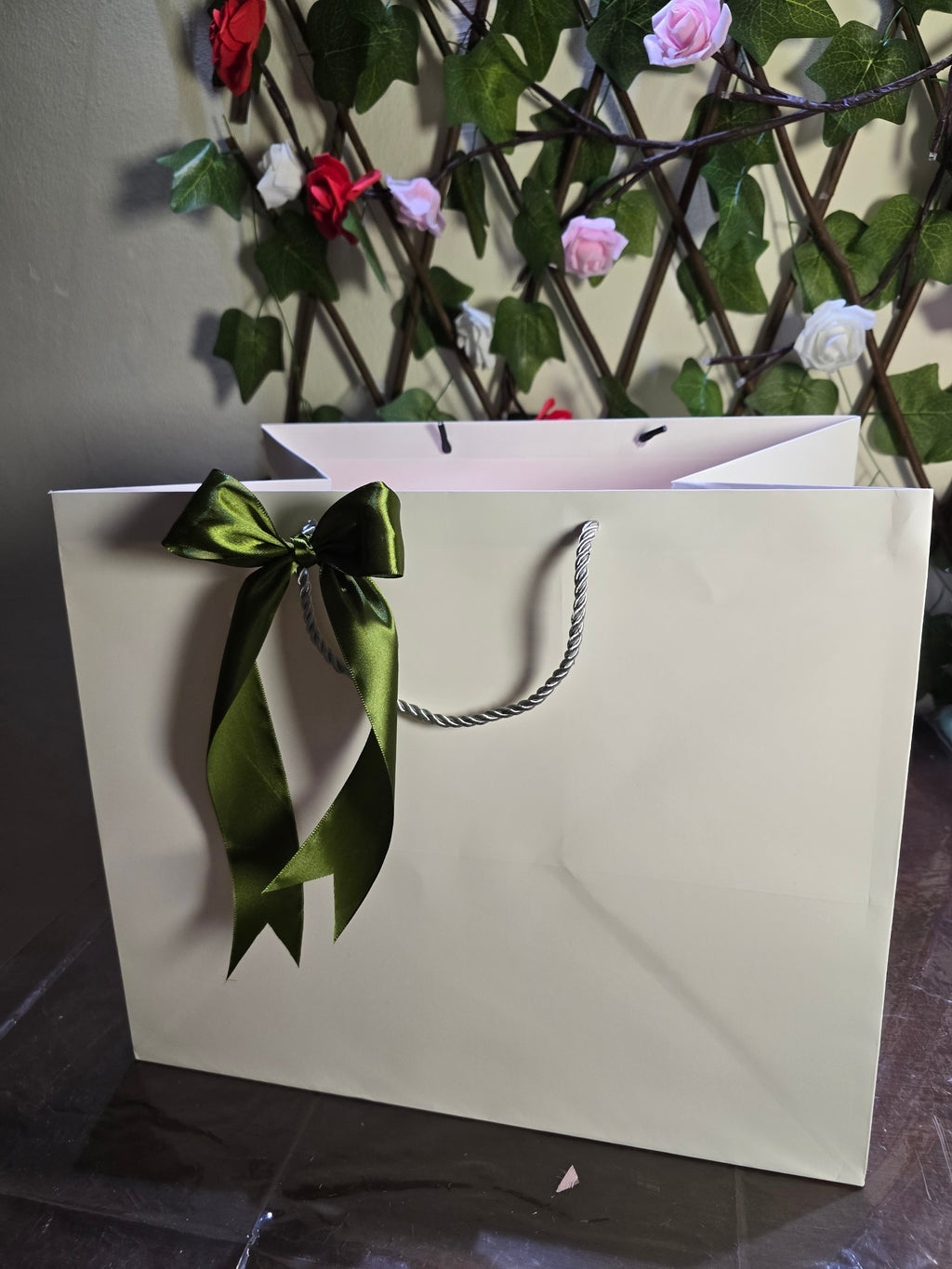 BioCode premium cream gift bag featuring a dark green satin ribbon bow, set against a floral trellis background.