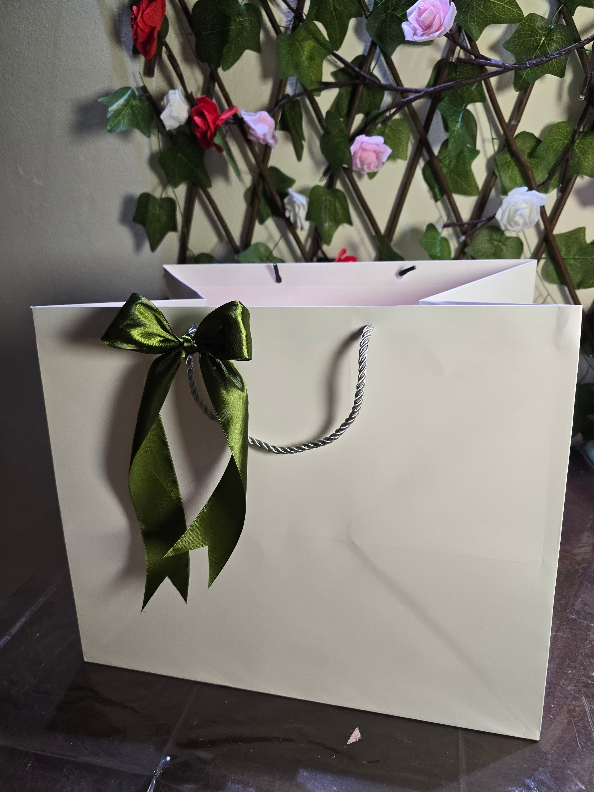 BioCode premium cream gift bag featuring a dark green satin ribbon bow, set against a floral trellis background.