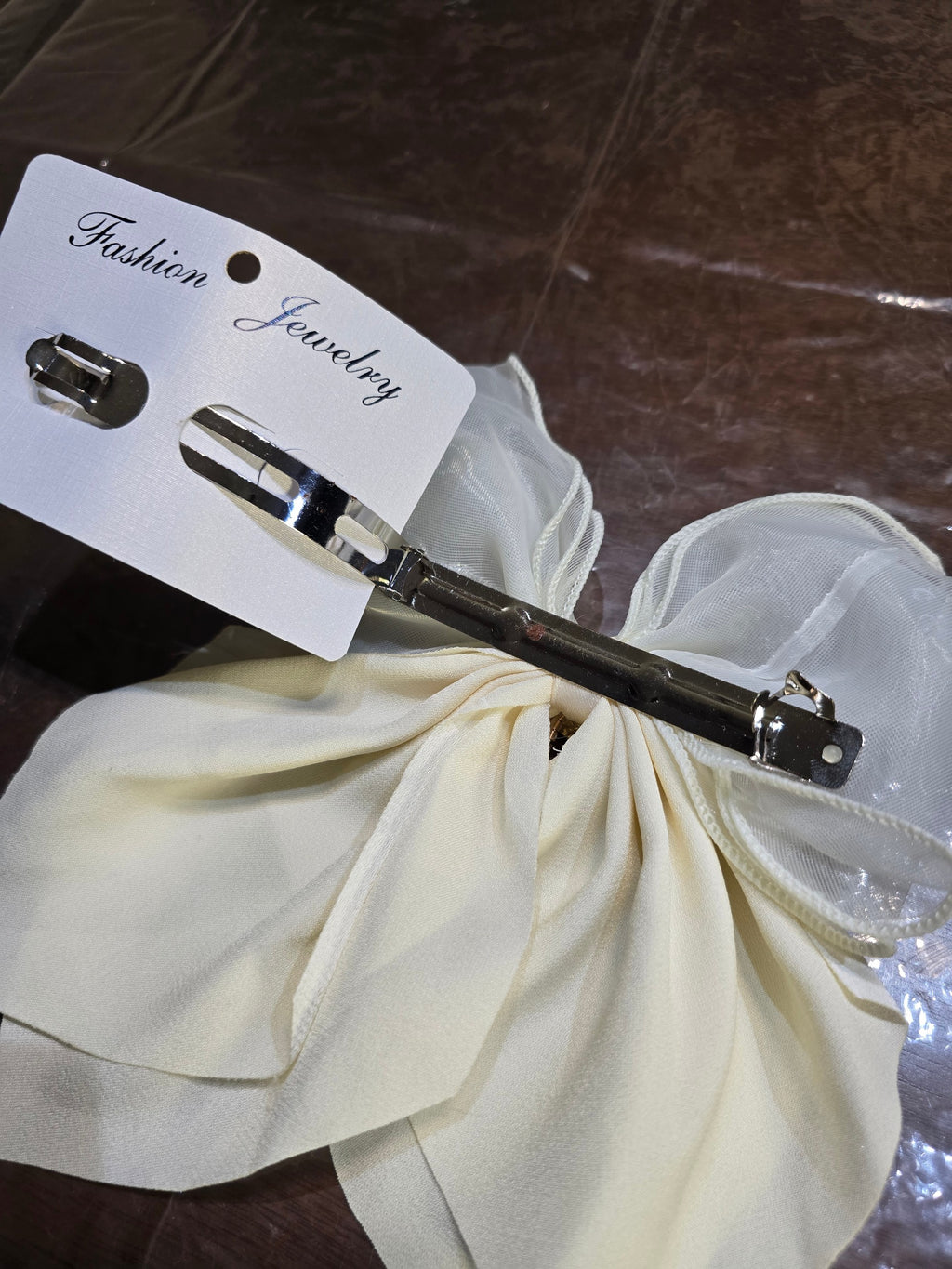 BioCode cream organza hair bow with a silver metal clip and rhinestone centre on a fashion jewellery display card
