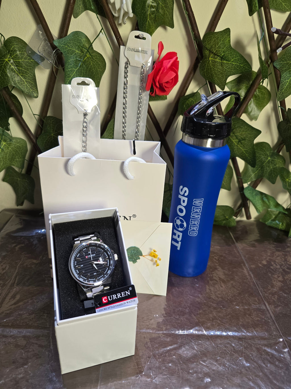 BioCode gift set featuring a Curren men's stainless steel watch, silver chain, and a blue sports water bottle.