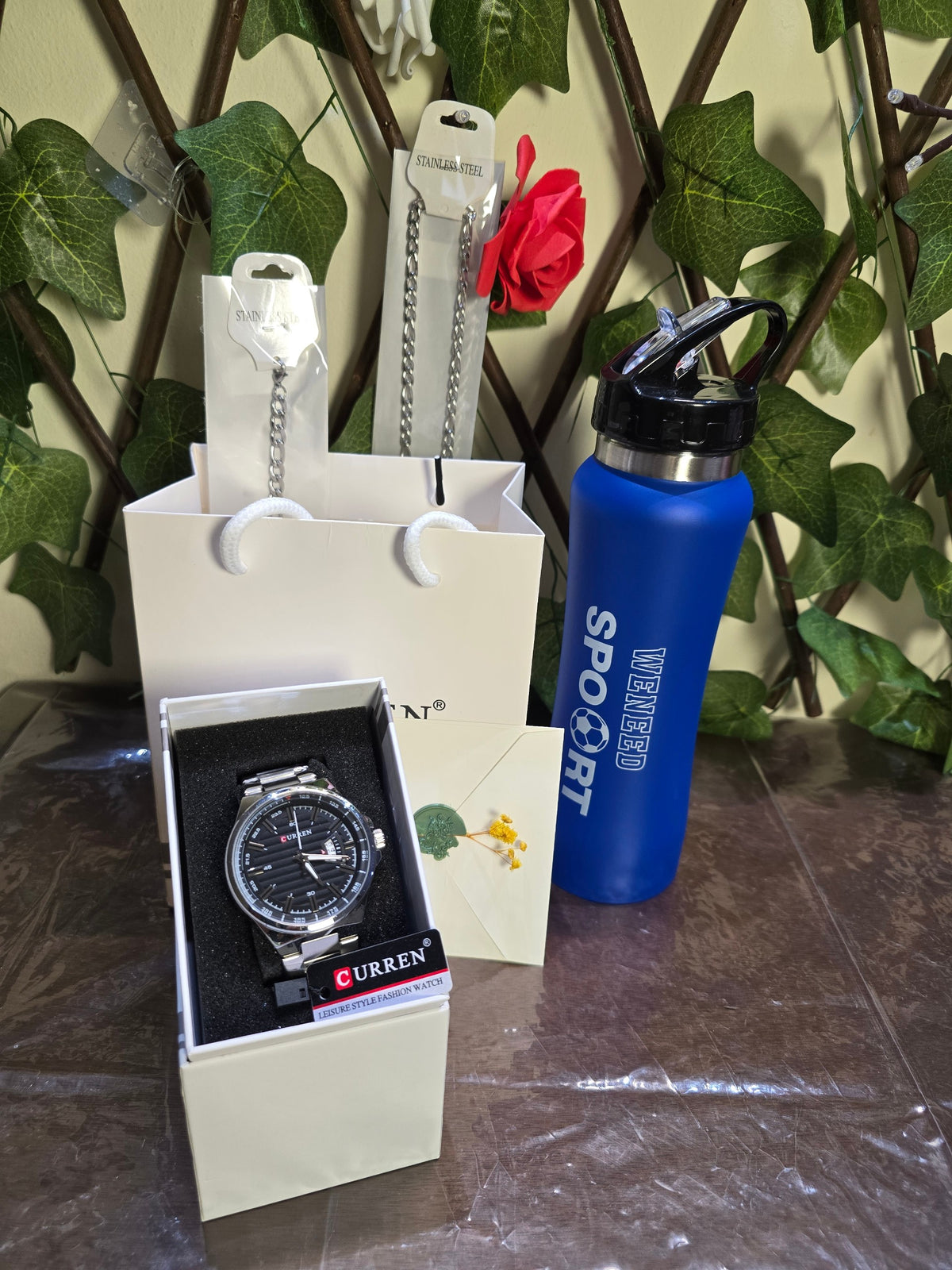 BioCode gift set featuring a Curren men's stainless steel watch, silver chain, and a blue sports water bottle.