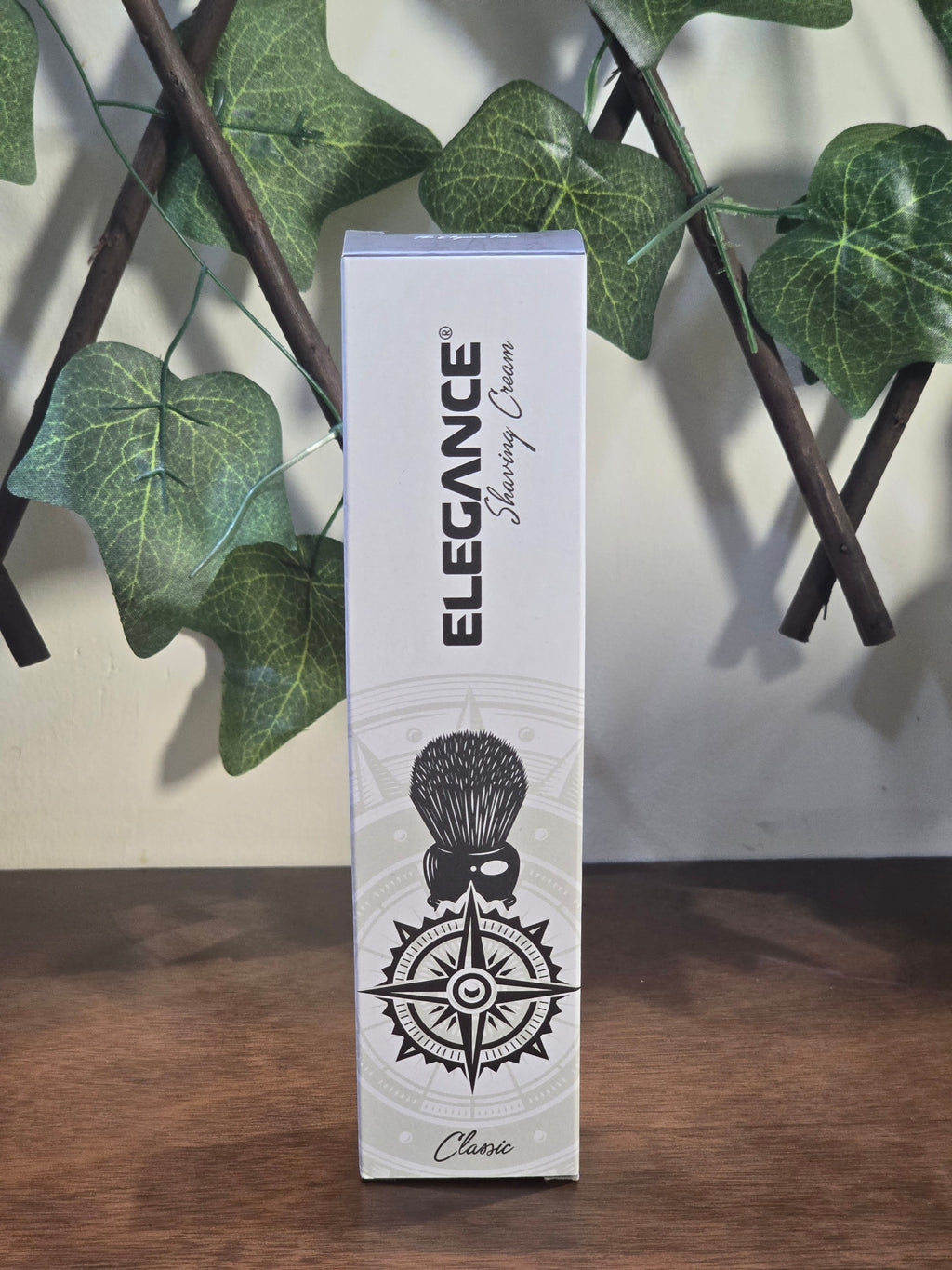 BioCode Elegance shaving cream box featuring a compass and brush graphic, displayed on a wooden surface.