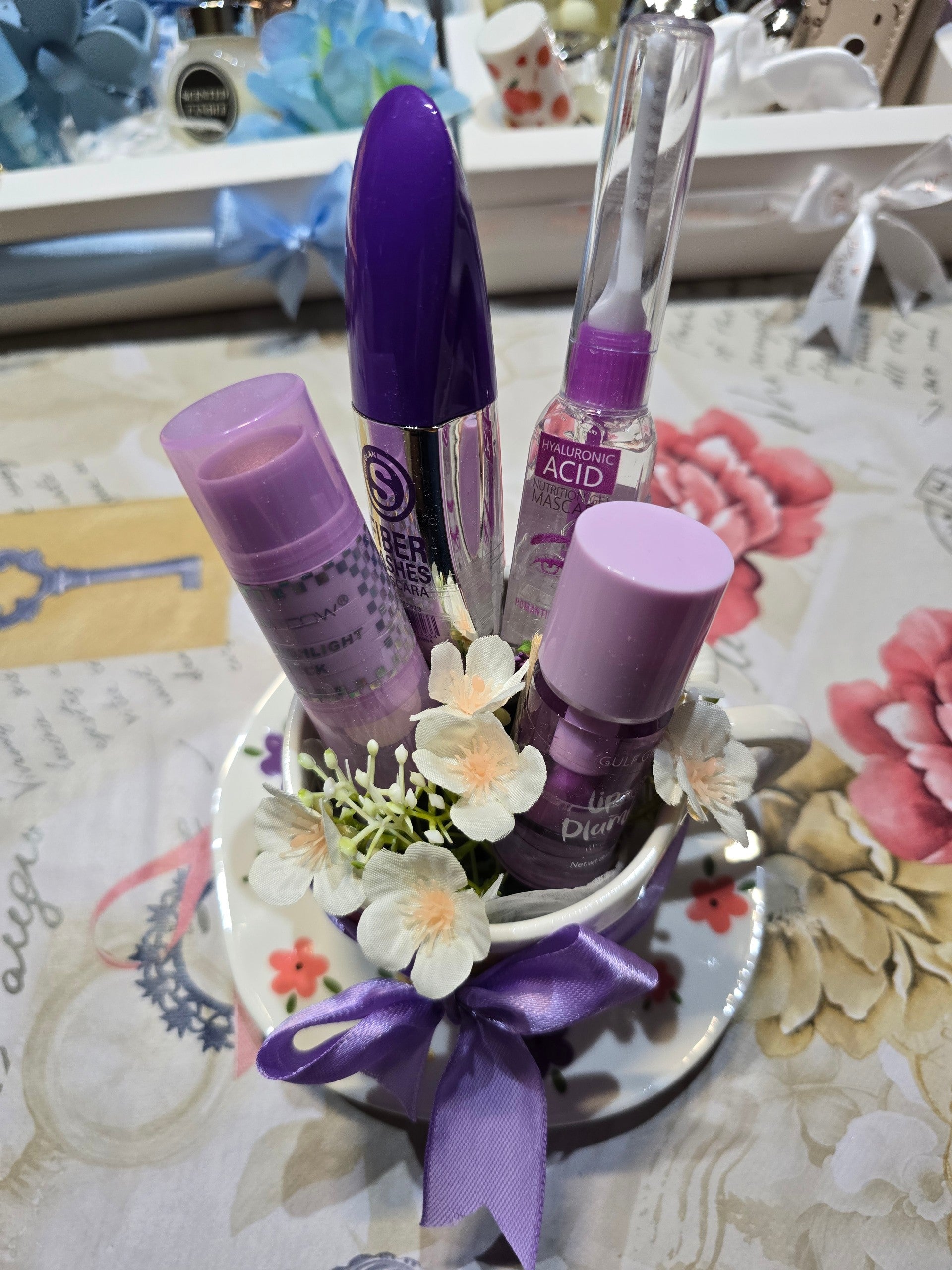BioCode beauty gift set featuring mascara, lash treatment, and lip plumper in a floral teacup with a purple ribbon.