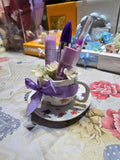 BioCode beauty gift set featuring mascara and lip plumper in a floral ceramic teacup with a purple ribbon bow.