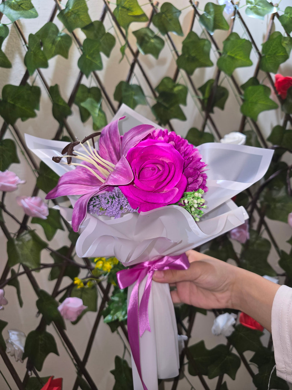 BioCode handcrafted artificial floral bouquet with fuchsia lily and rose, wrapped in white paper with a satin ribbon.