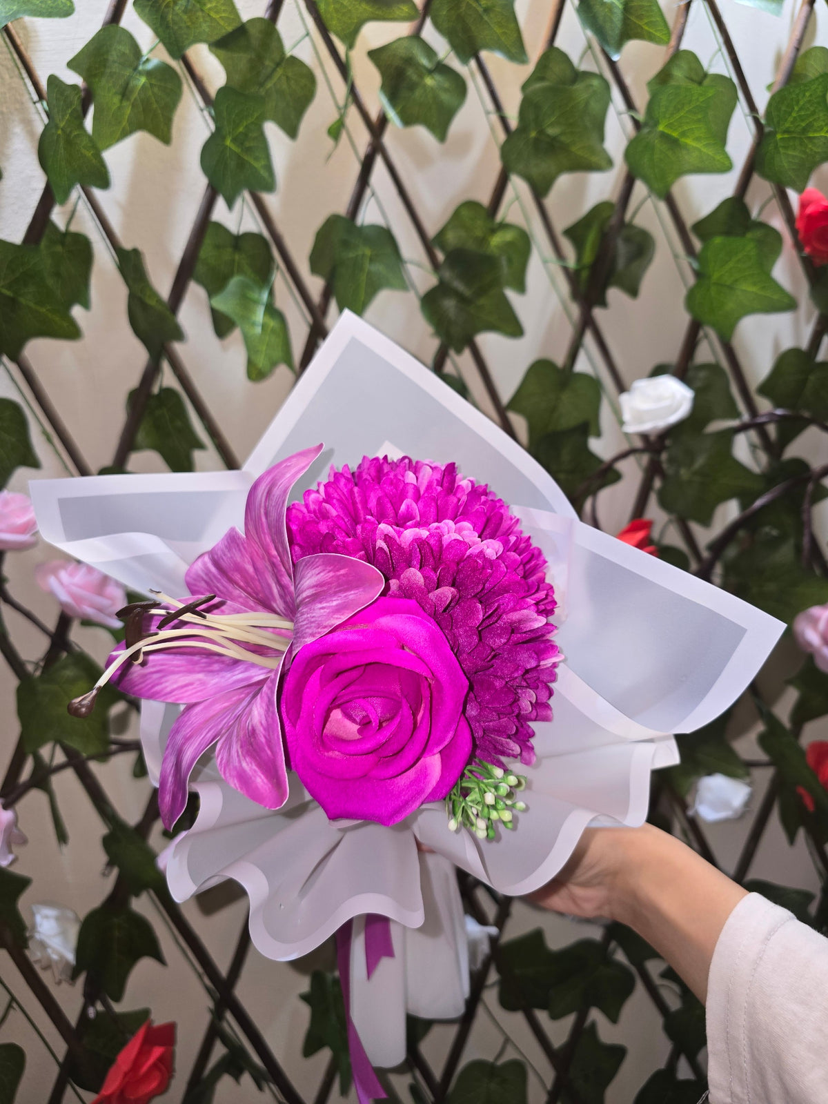 BioCode handcrafted artificial floral bouquet with fuchsia lily and rose wrapped in white paper with a satin ribbon