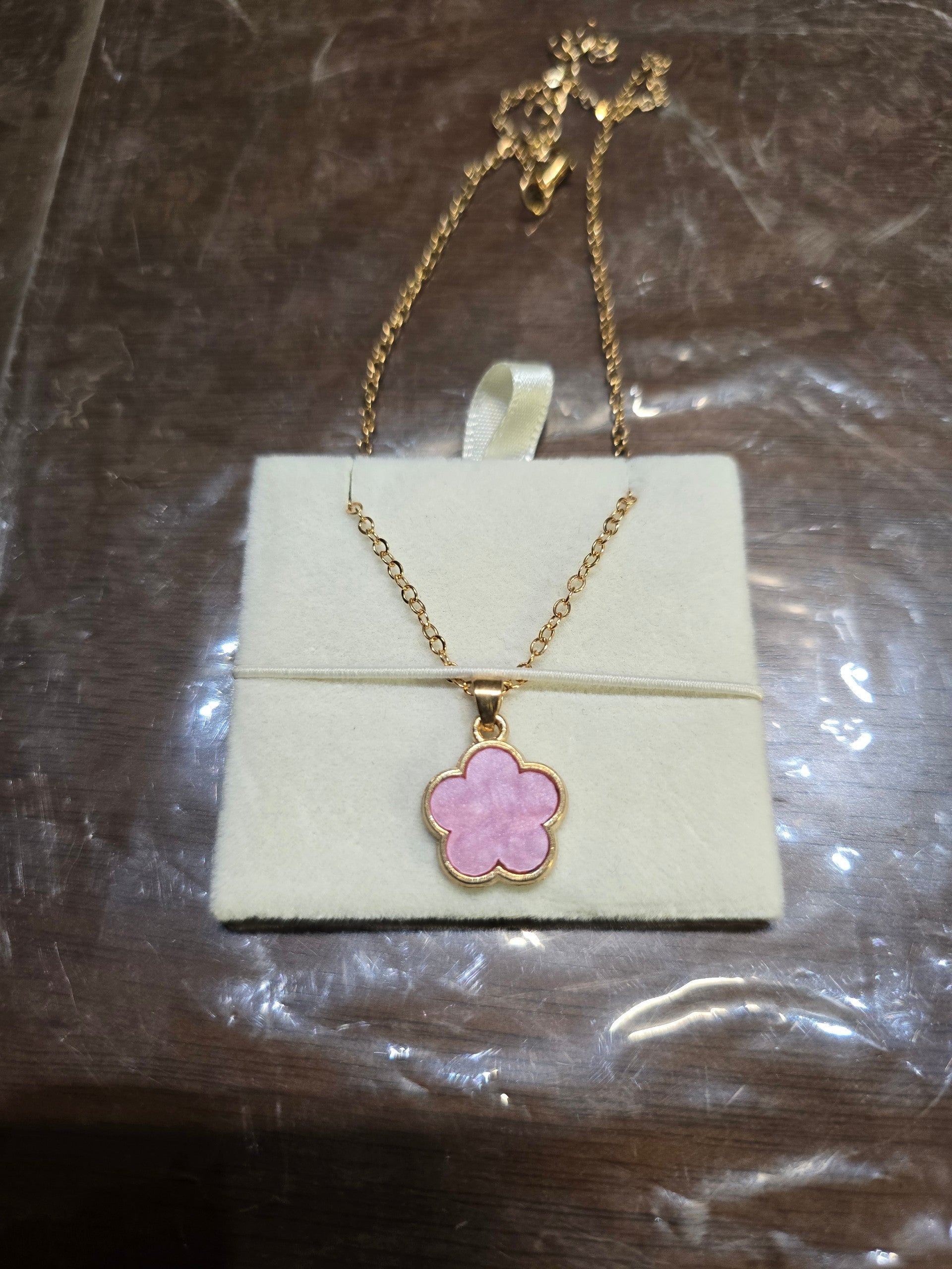 BioCode gold chain necklace featuring a delicate pink floral pendant displayed on a soft cream velvet jewellery card