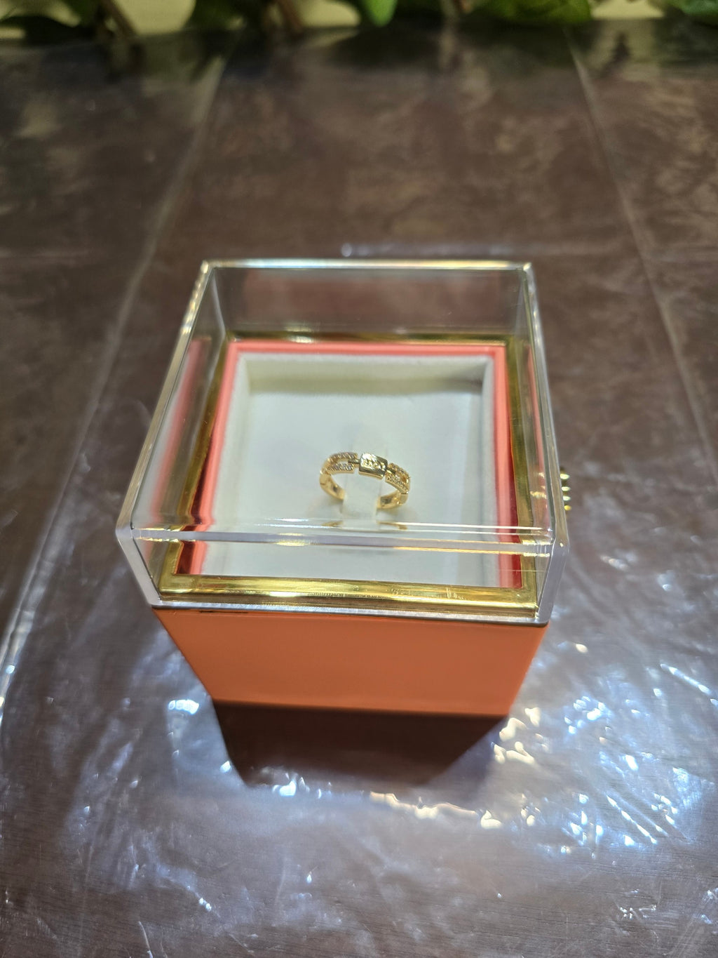 BioCode gold ring with crystal accents displayed in a clear square gift box with a soft pink base