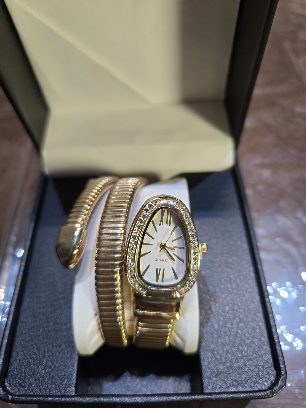 BioCode gold-tone snake-inspired coil watch with crystal bezel and white dial displayed in a black gift box