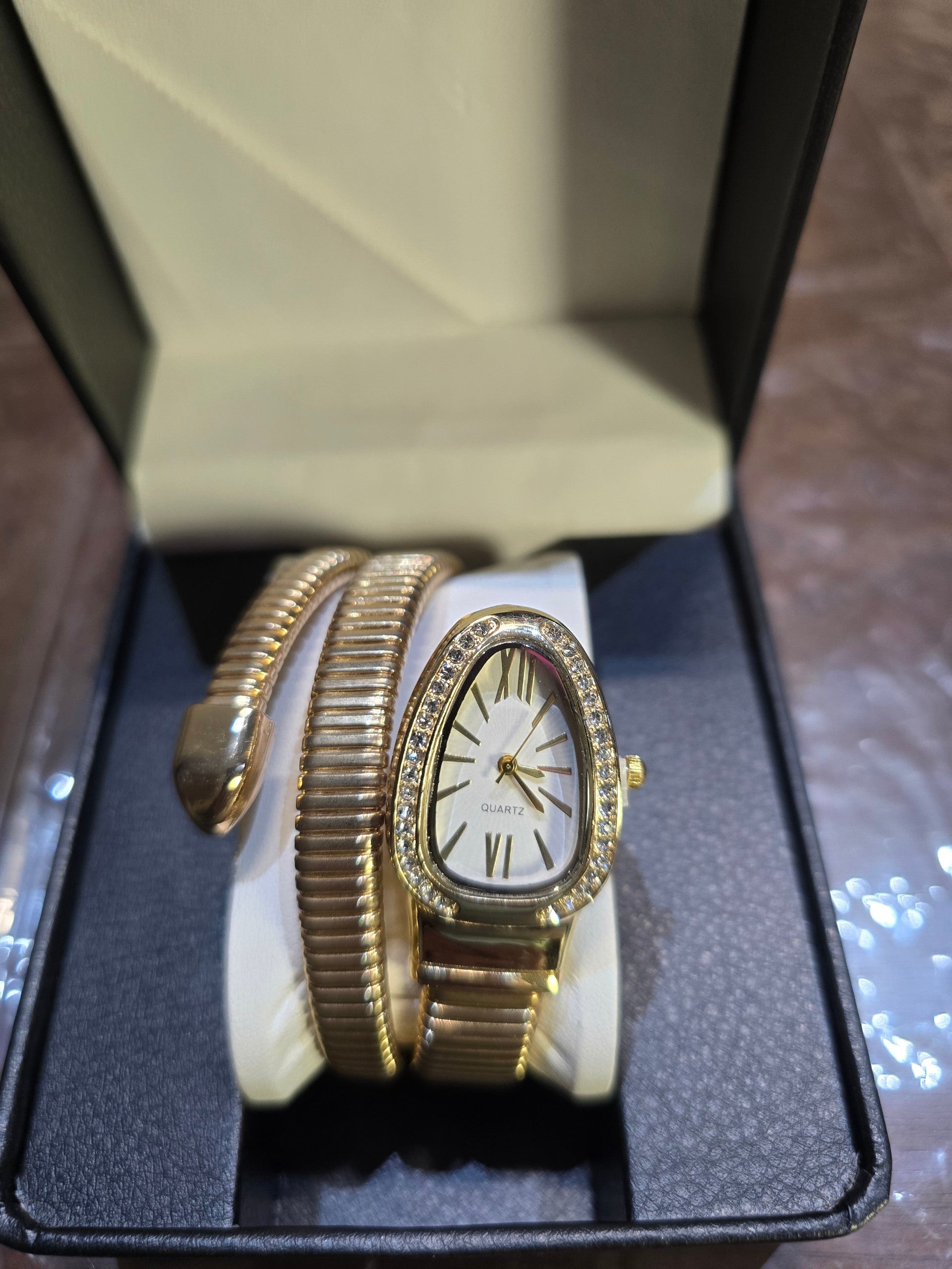 BioCode gold-tone snake-inspired coil watch with crystal bezel and white dial displayed in a black gift box