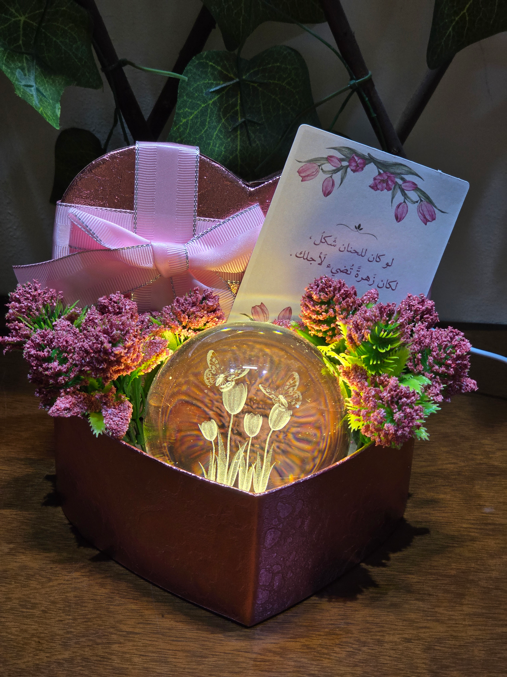 BioCode heart-shaped gift box with a glowing glass crystal sphere, pink flowers, and a romantic greeting card.