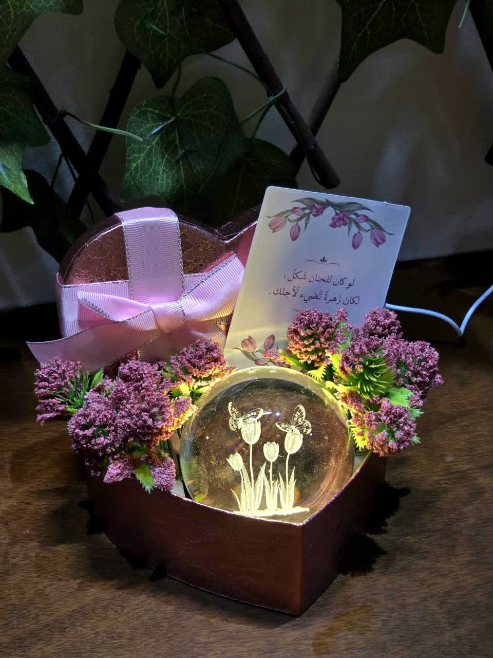 BioCode heart-shaped gift box with a glowing glass sphere, pink floral accents, satin ribbon, and a greeting card.