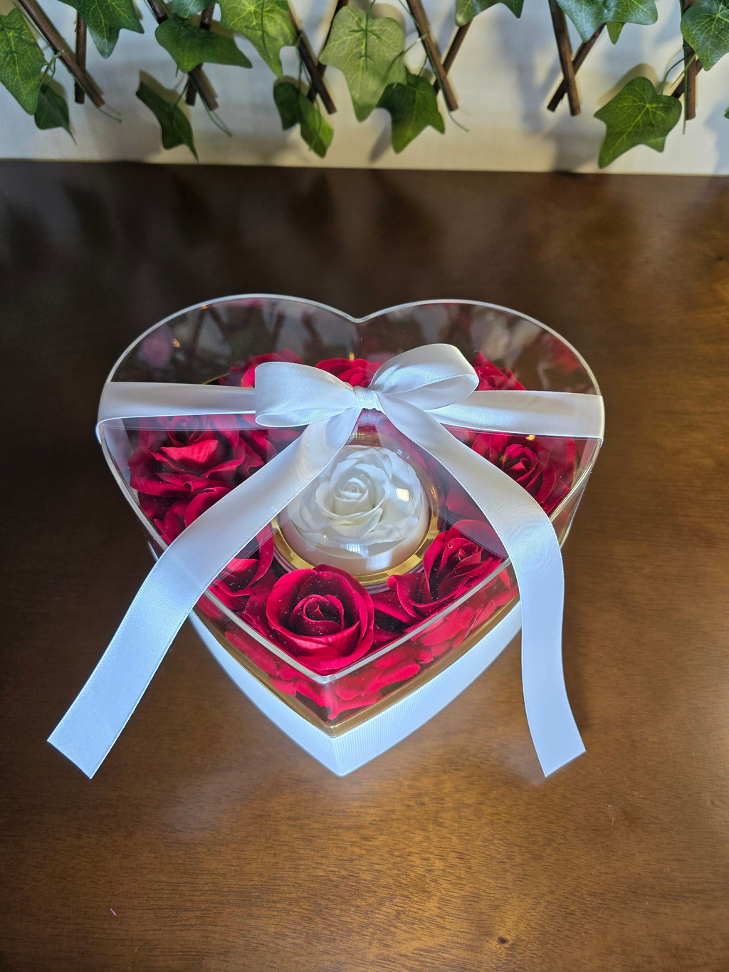 BioCode heart-shaped gift box with preserved red roses and a central white rose in a clear acrylic case with a ribbon