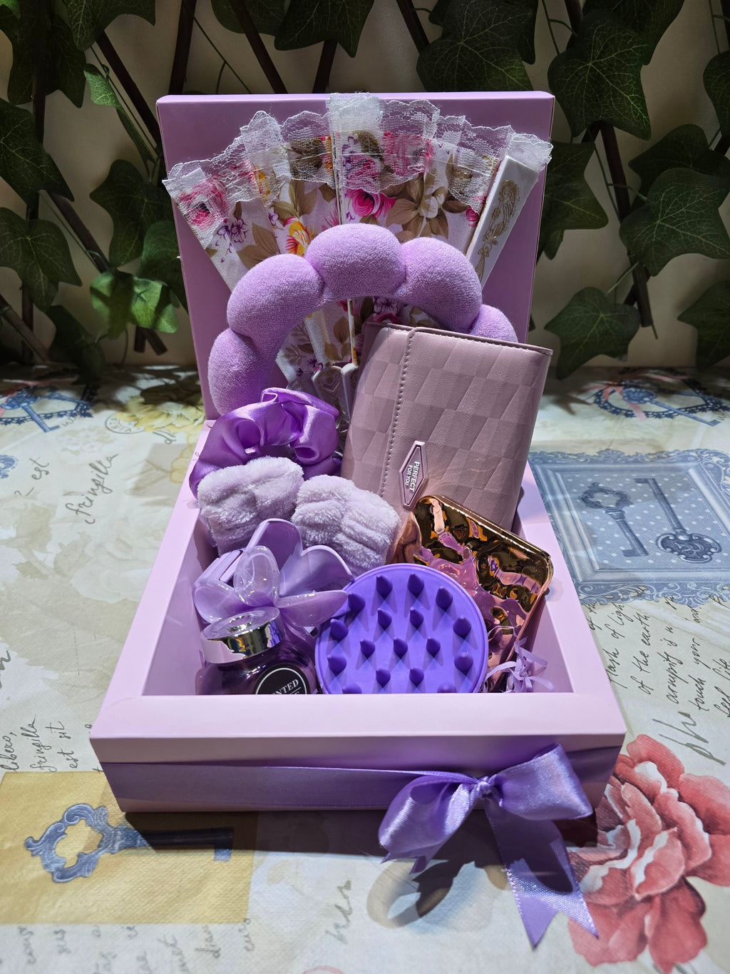 BioCode lilac self-care gift set featuring a headband, wrist cuffs, scalp massager, mirror, wallet, and lace fan.