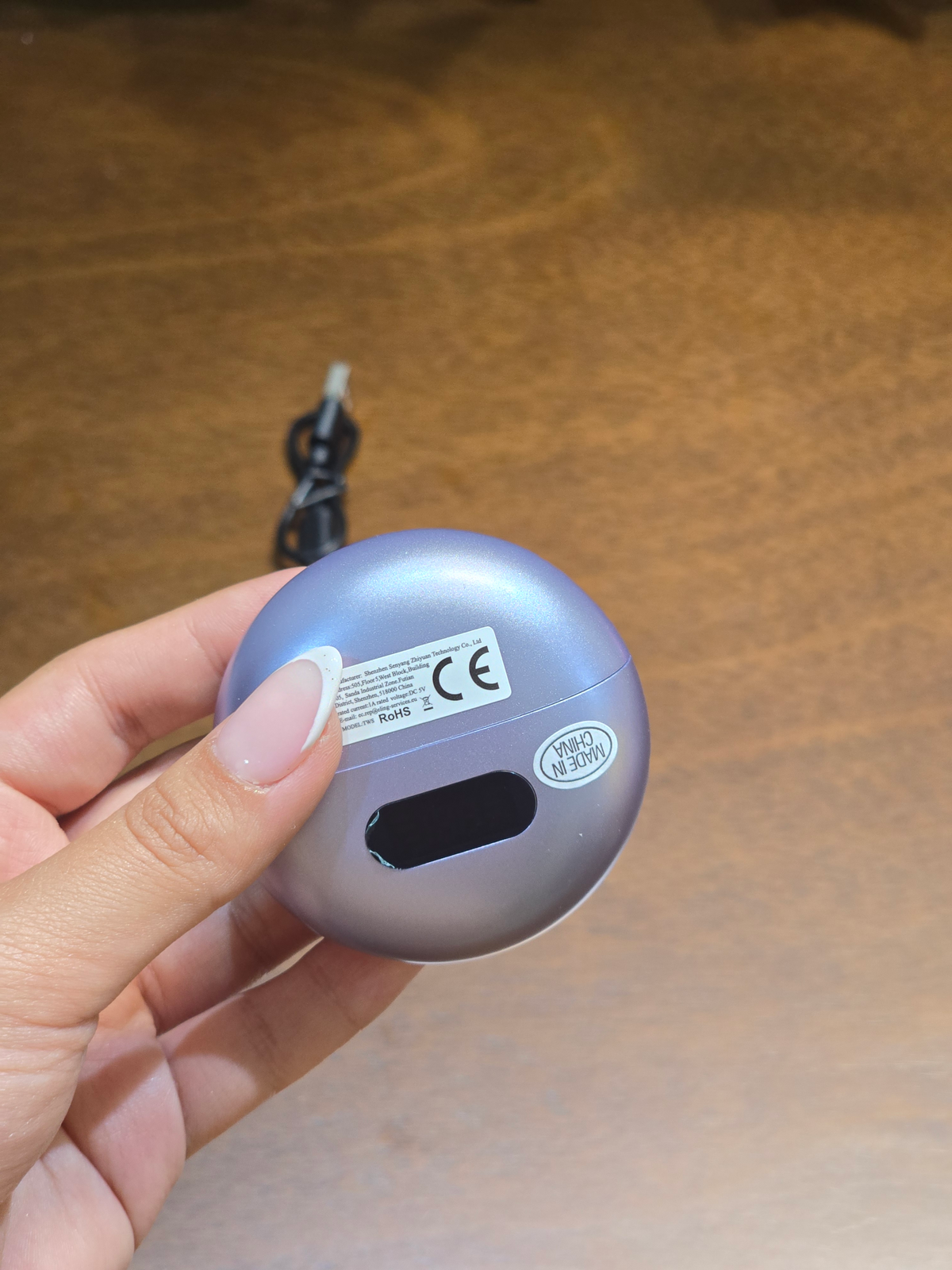 BioCode lilac wireless earbud charging case with digital display held in hand