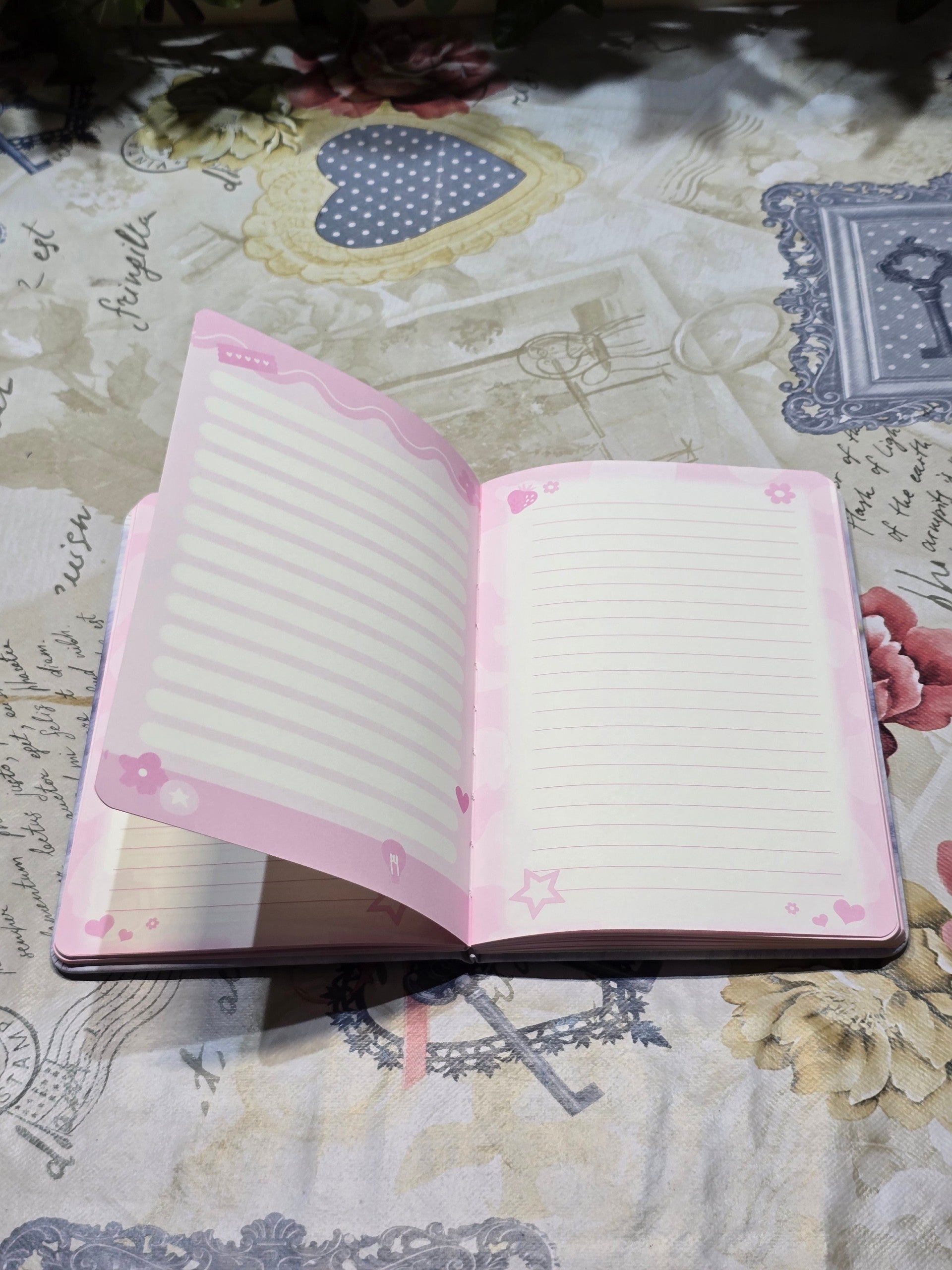 BioCode open notebook with lined pages featuring pastel pink floral and star motifs on a vintage-style patterned cloth