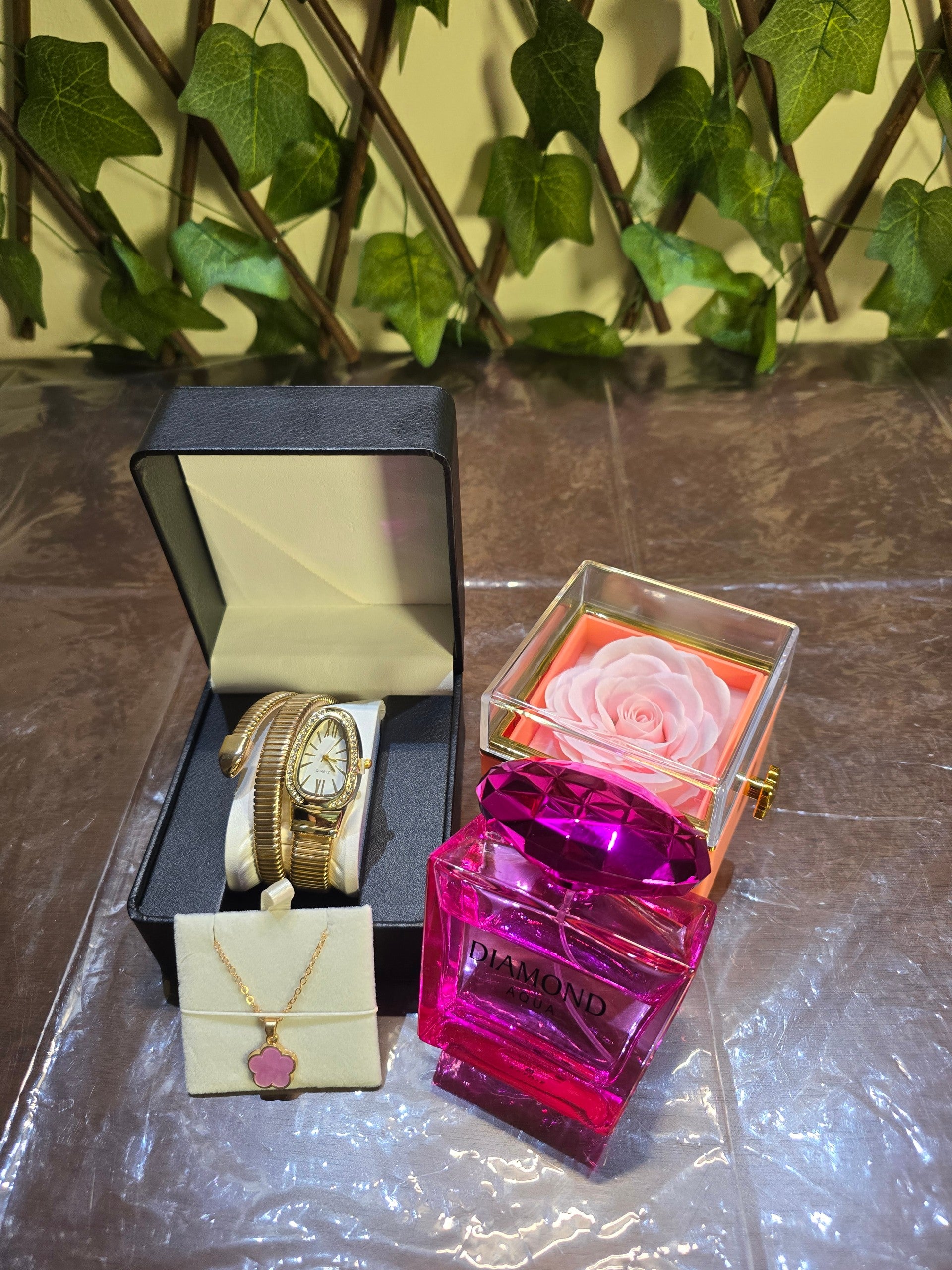 BioCode luxury gift set featuring Diamond Aqua perfume, gold snake watch, floral necklace, ring, and preserved rose.
