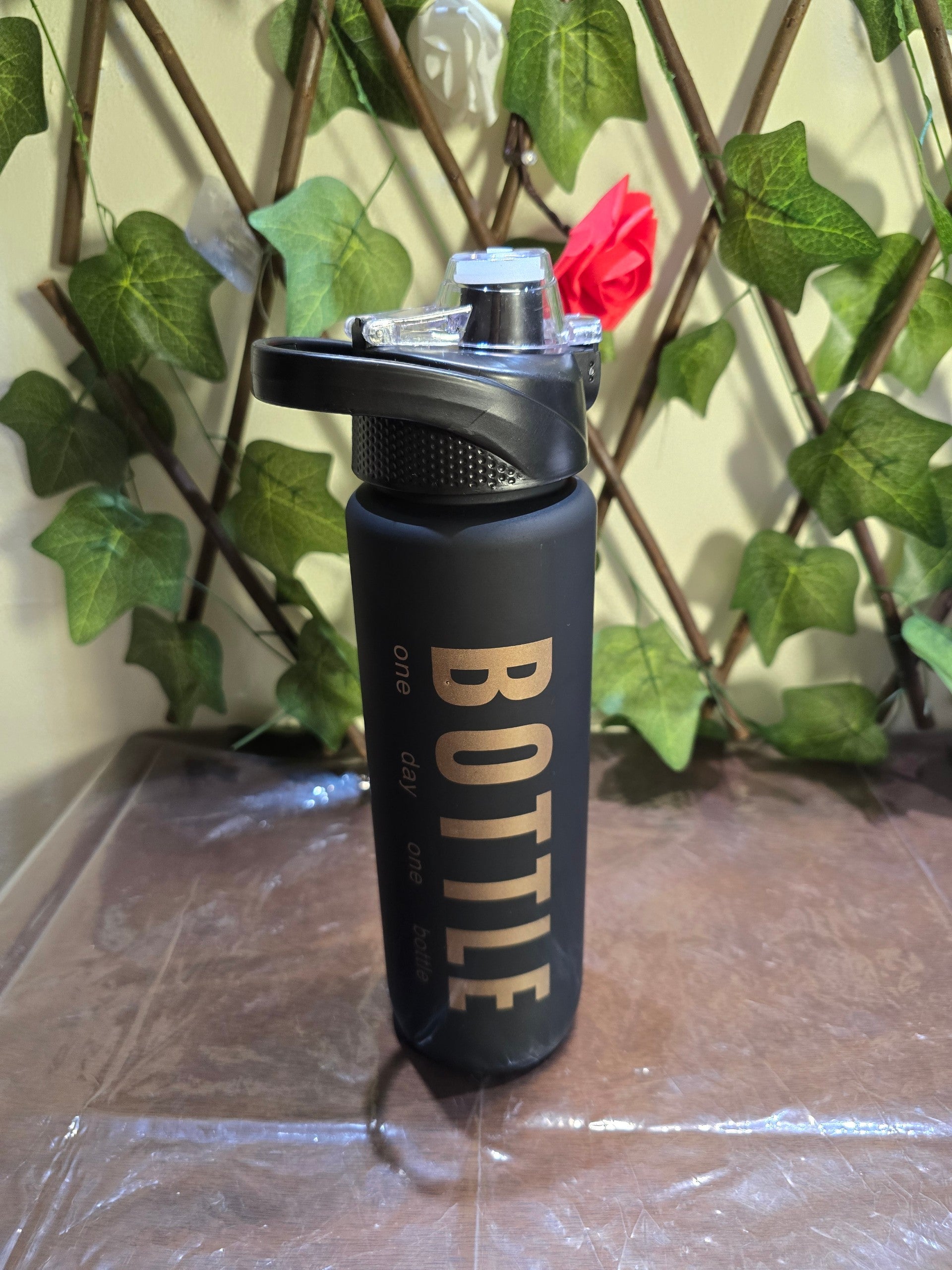BioCode matte black 1000ml hydration bottle with gold typography and a secure flip-top lid