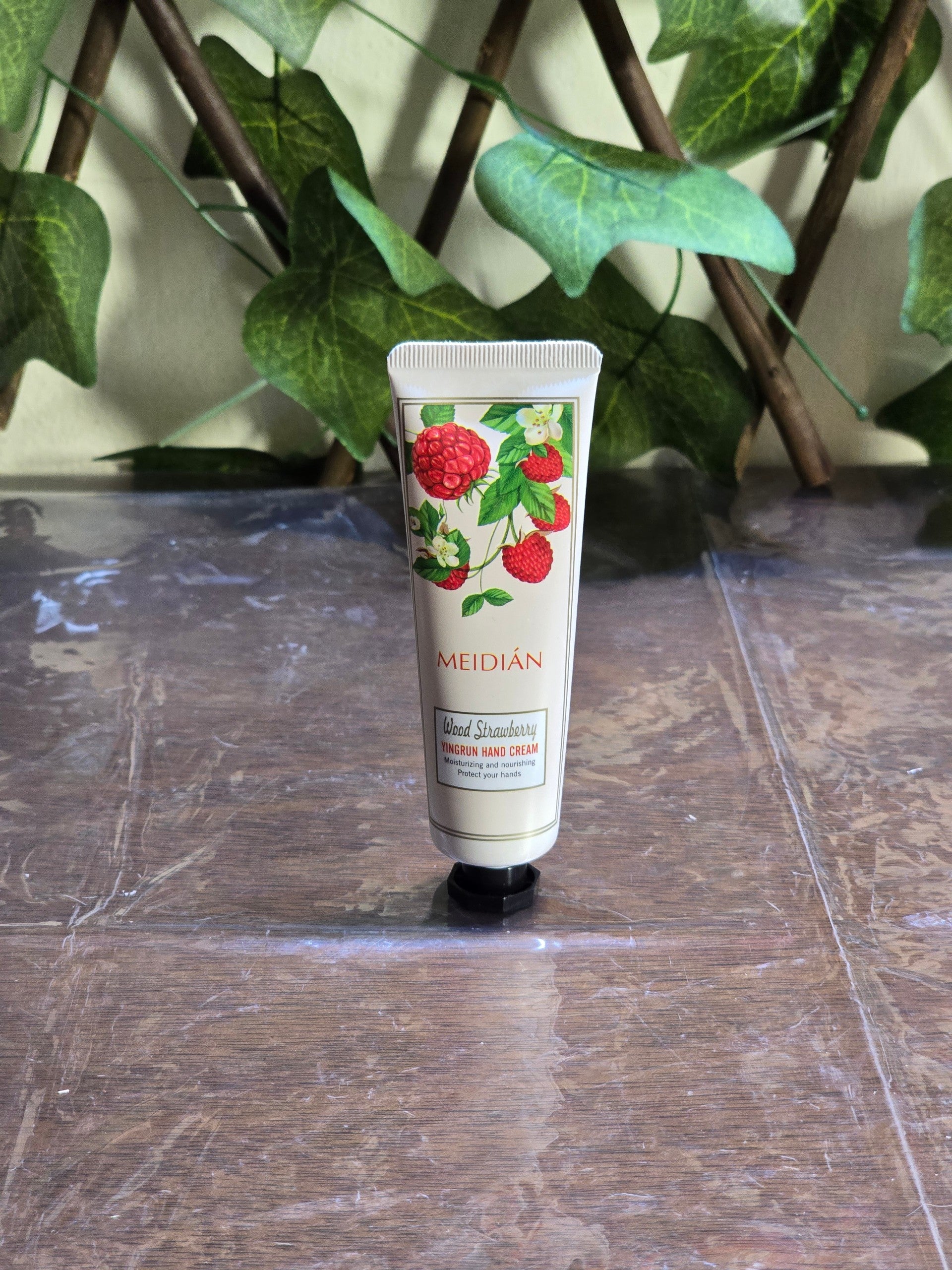 BioCode Meidián Wood Strawberry hand cream tube featuring a botanical raspberry illustration on a wooden surface.