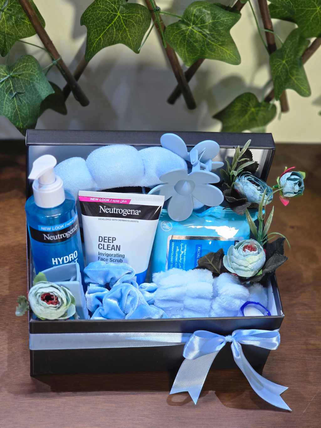 BioCode Neutrogena skincare gift set featuring blue cleanser, face scrub, plush headband, and hair accessories in a box