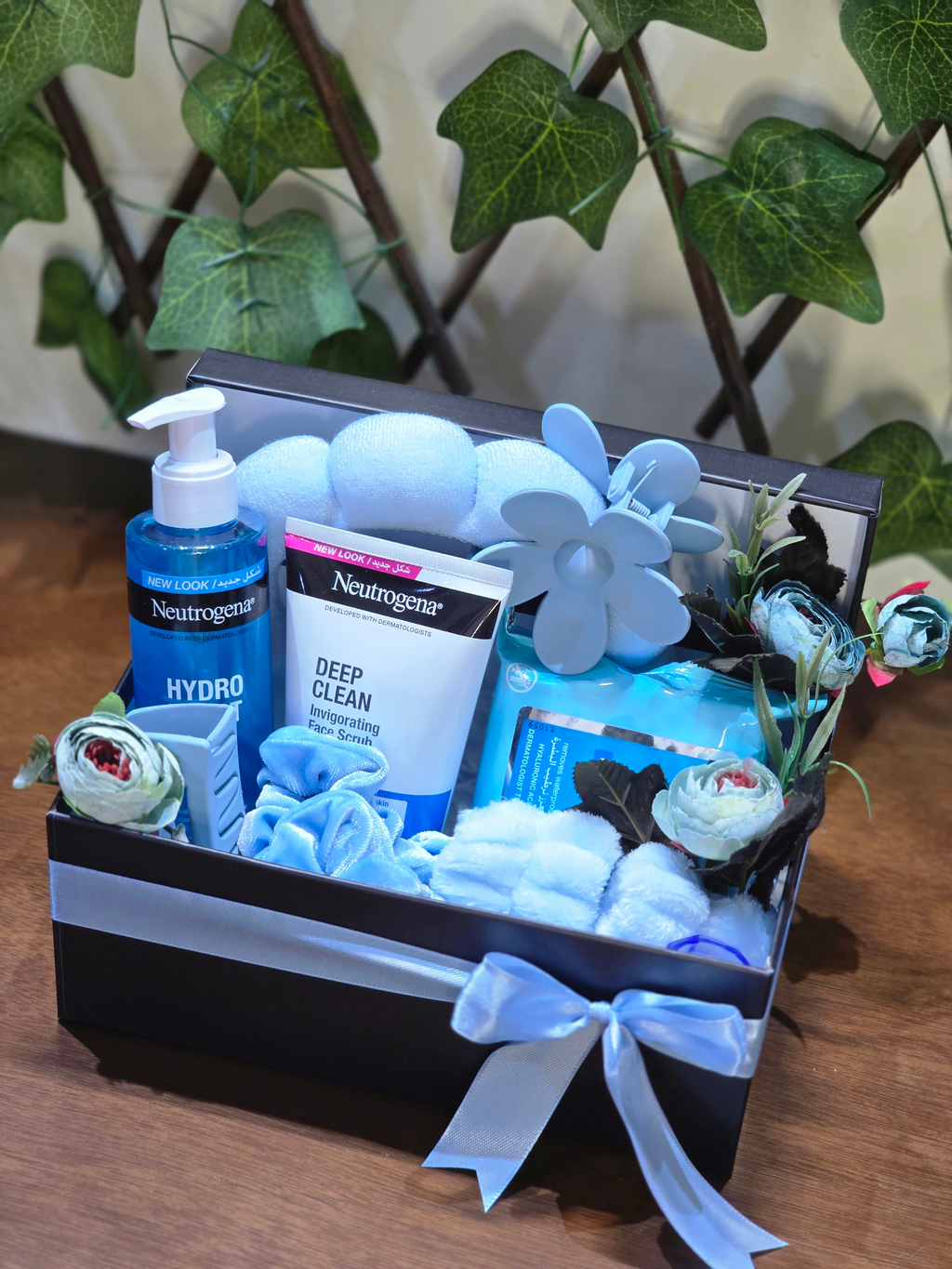 BioCode Neutrogena skincare gift set in a black box with blue ribbon, featuring cleanser, scrub, and hair accessories.