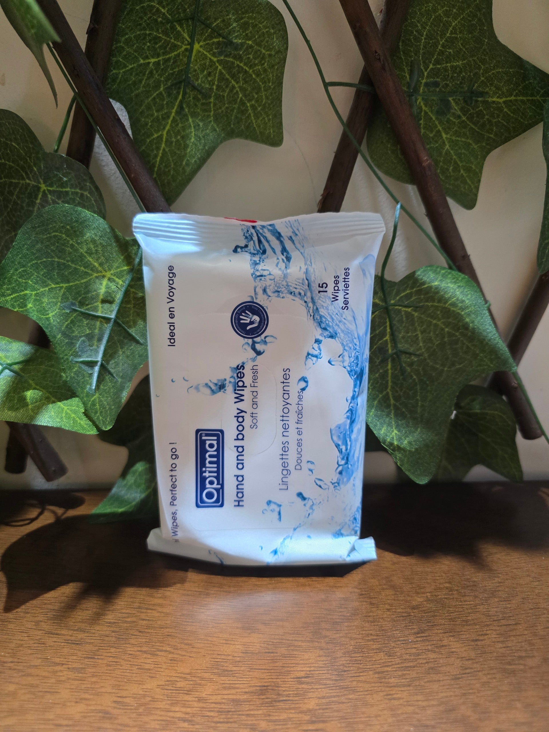 BioCode Optimal hand and body wipes in a white travel-sized pack with blue water splash design against green leaves