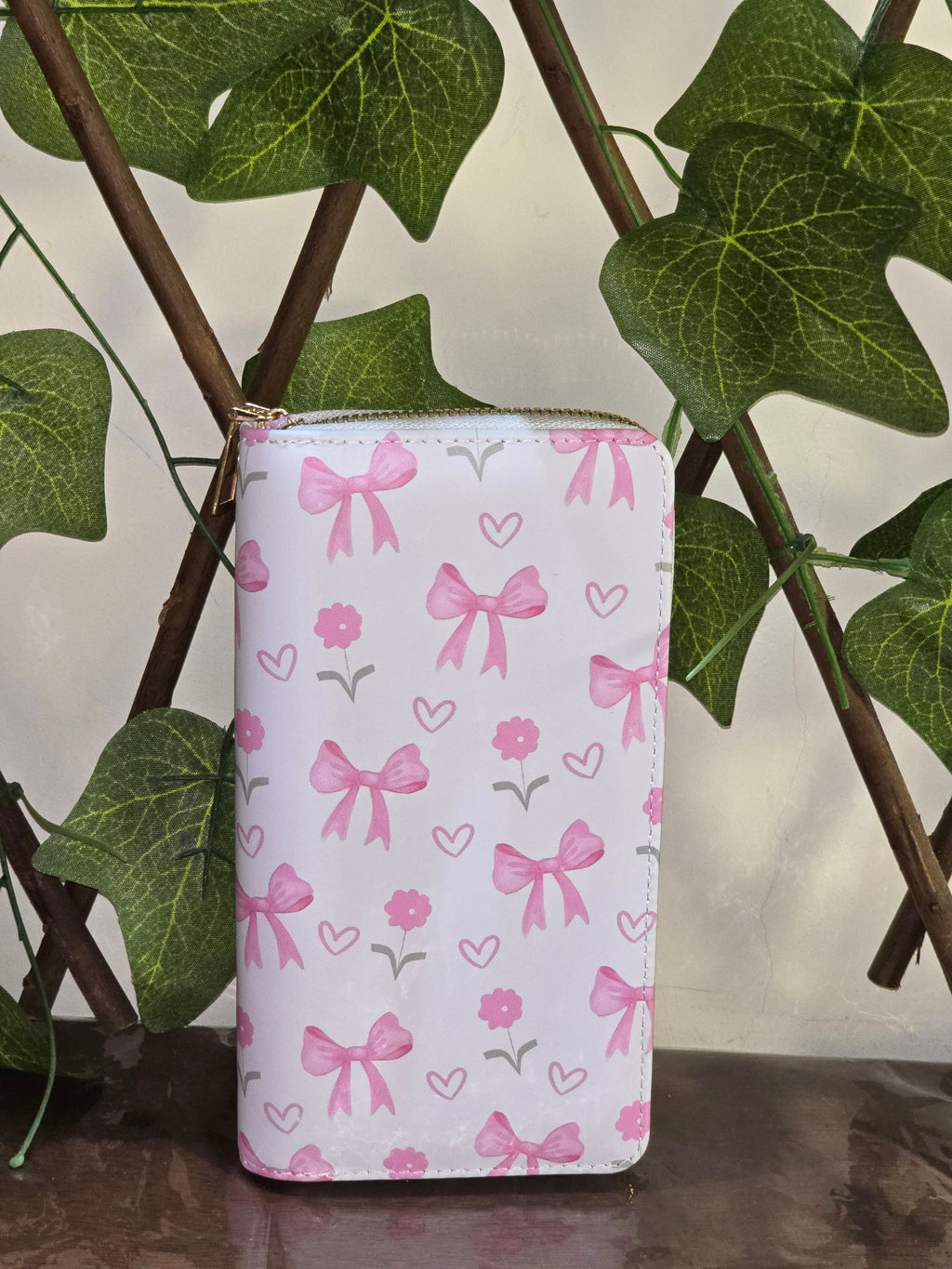 BioCode pink and white wallet featuring a whimsical bow and flower pattern, displayed against a decorative ivy trellis.