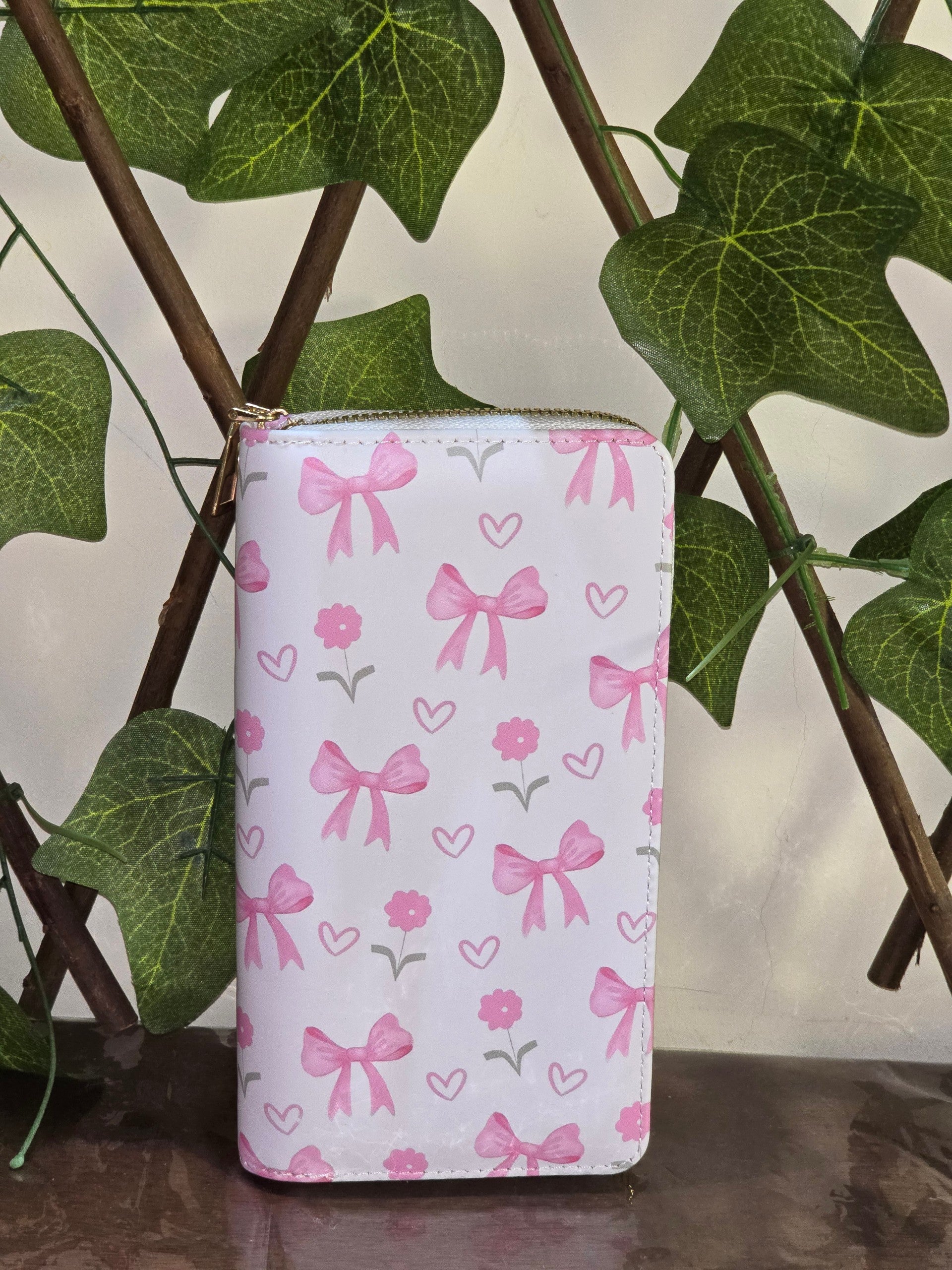 BioCode pink and white wallet featuring a whimsical bow and flower pattern, displayed against a decorative ivy trellis.