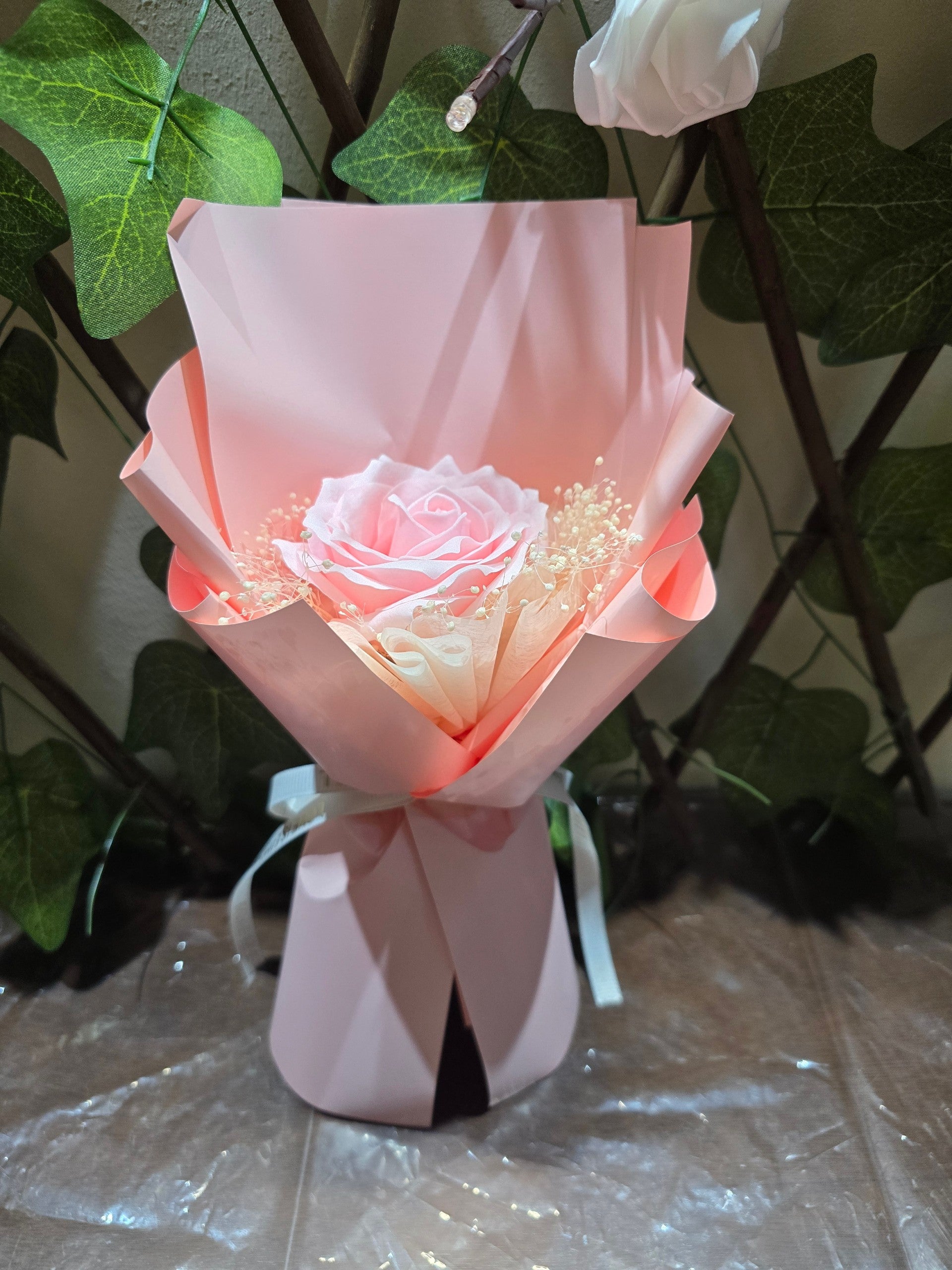 BioCode pink eternity rose bouquet with baby's breath in a decorative paper wrap and white ribbon