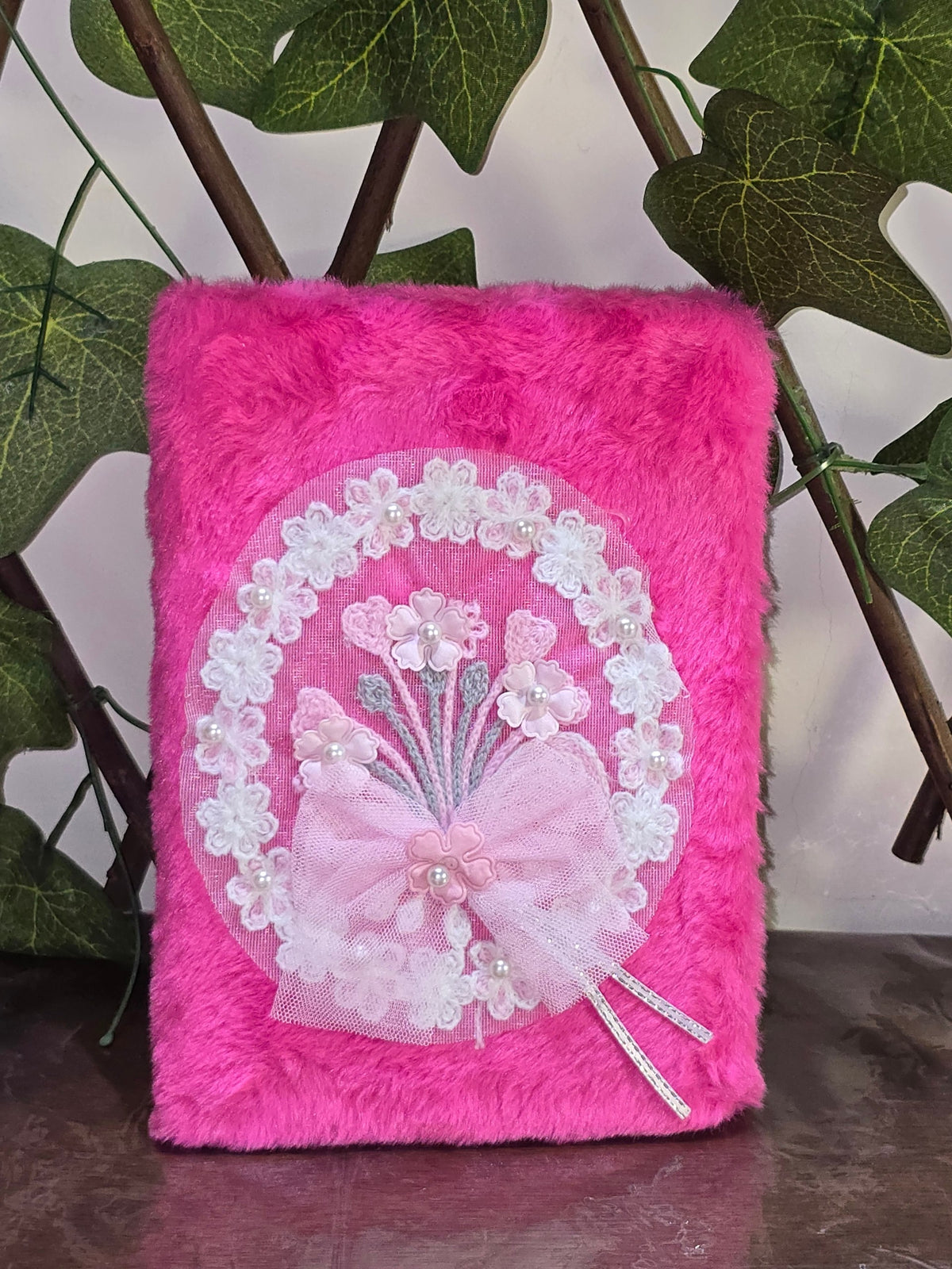 BioCode pink fuzzy notebook with lace floral applique, pearl accents, and a bow detail on the front cover.
