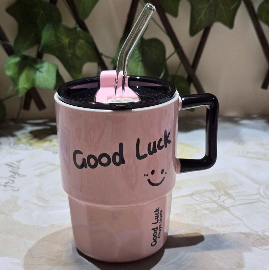 BioCode pastel pink insulated mug with a black handle, lid, glass straw, and Good Luck smiley face print