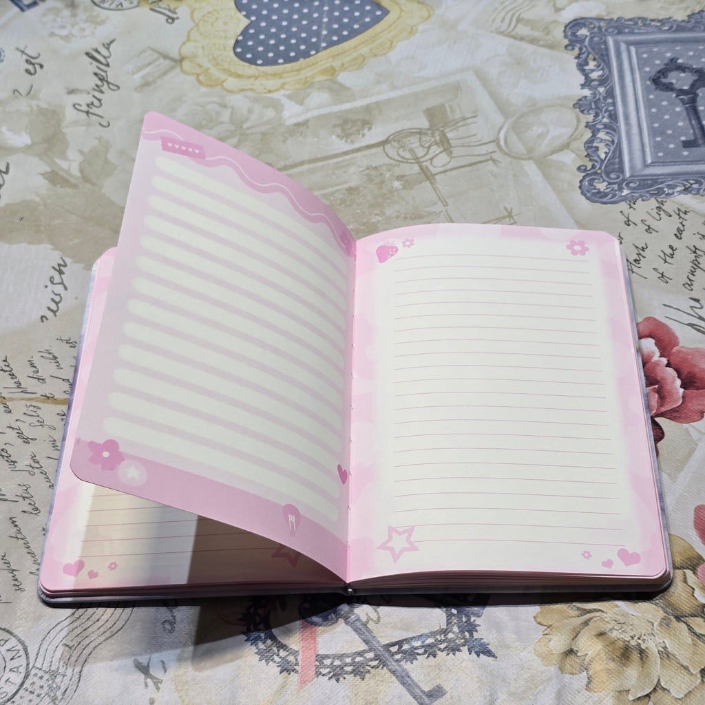 BioCode open notebook with pastel pink lined pages featuring cute star, heart, and flower motifs on a patterned cloth