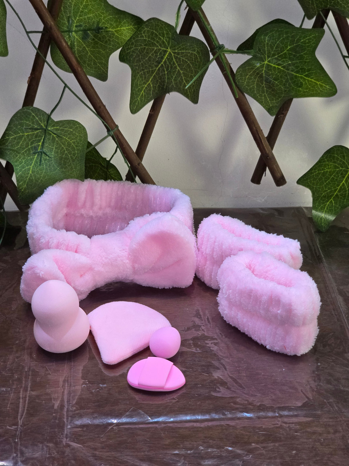 BioCode pink plush spa headband and wristband set with soft makeup sponges and facial tools on a reflective surface