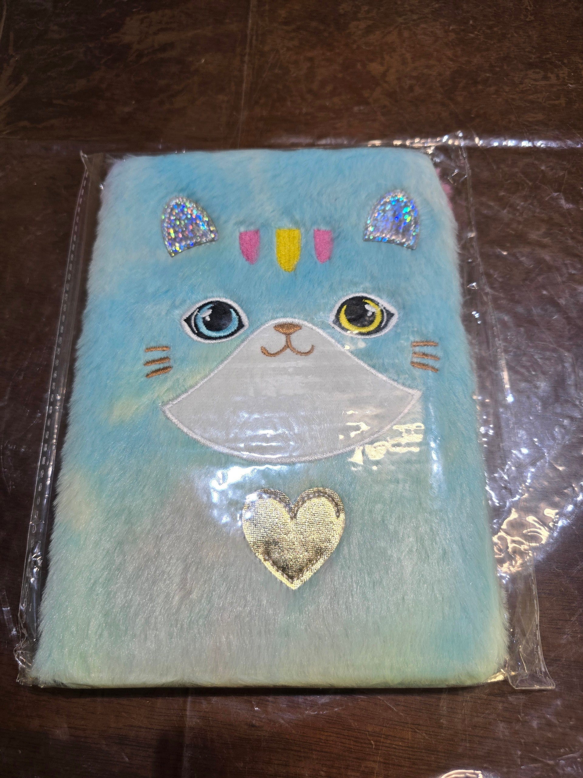 BioCode plush blue cat-themed notebook with fuzzy texture, embroidered facial details, and a gold heart embellishment.