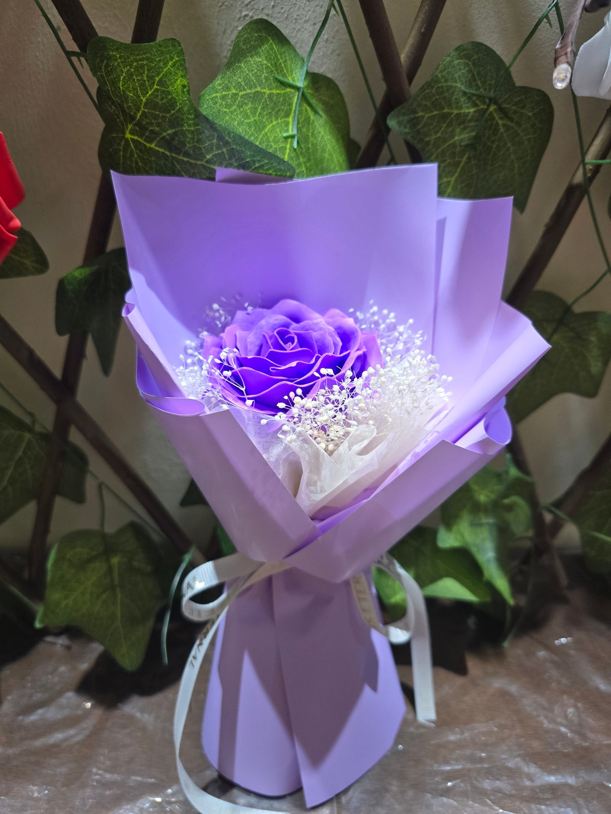 BioCode purple eternity rose bouquet with baby's breath in matching paper wrap and white ribbon