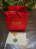BioCode red gift bag with gold text and a cream envelope sealed with a green wax stamp and dried yellow flowers