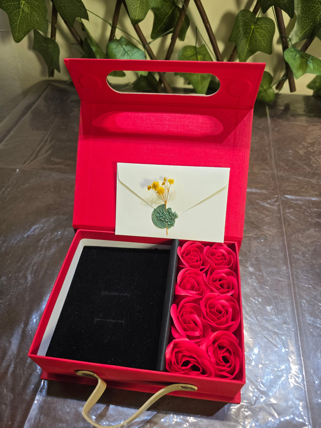 BioCode red gift box with artificial roses, black velvet jewellery insert, and a wax-sealed envelope for notes.