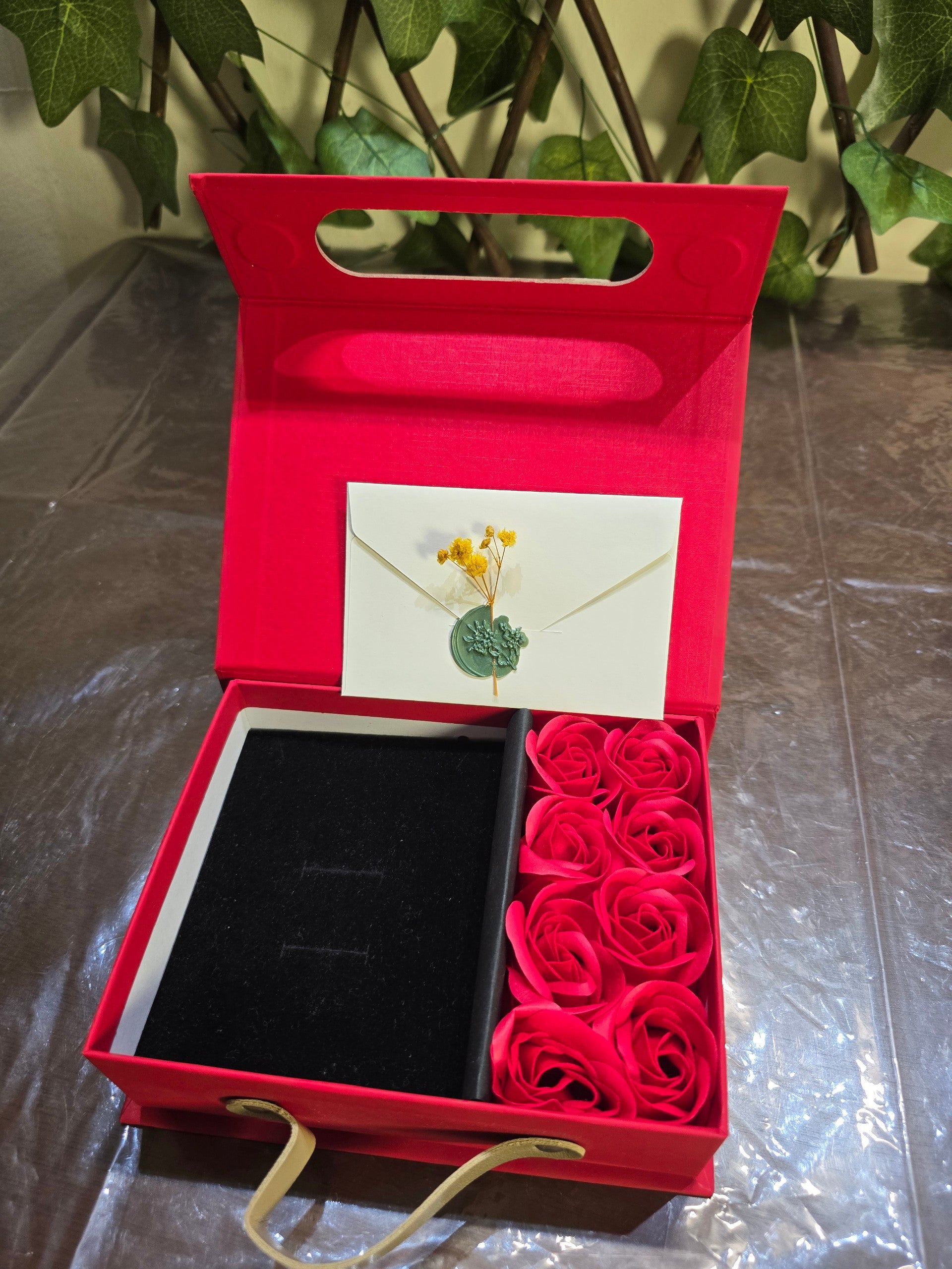 BioCode red gift box with artificial roses, black velvet jewellery insert, and a wax-sealed envelope for notes.