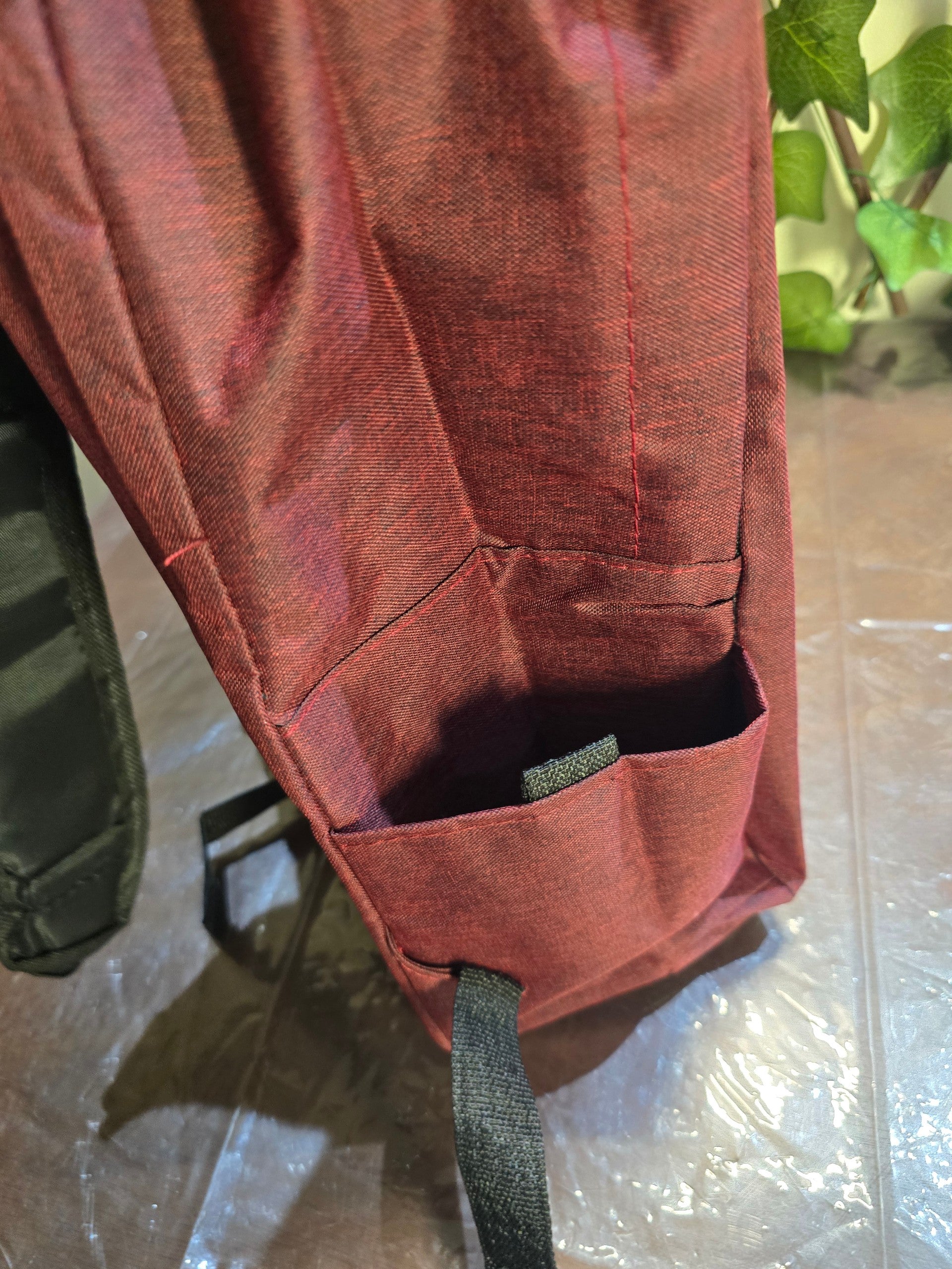 BioCode deep red laptop backpack side view showing a durable fabric side pocket for a water bottle