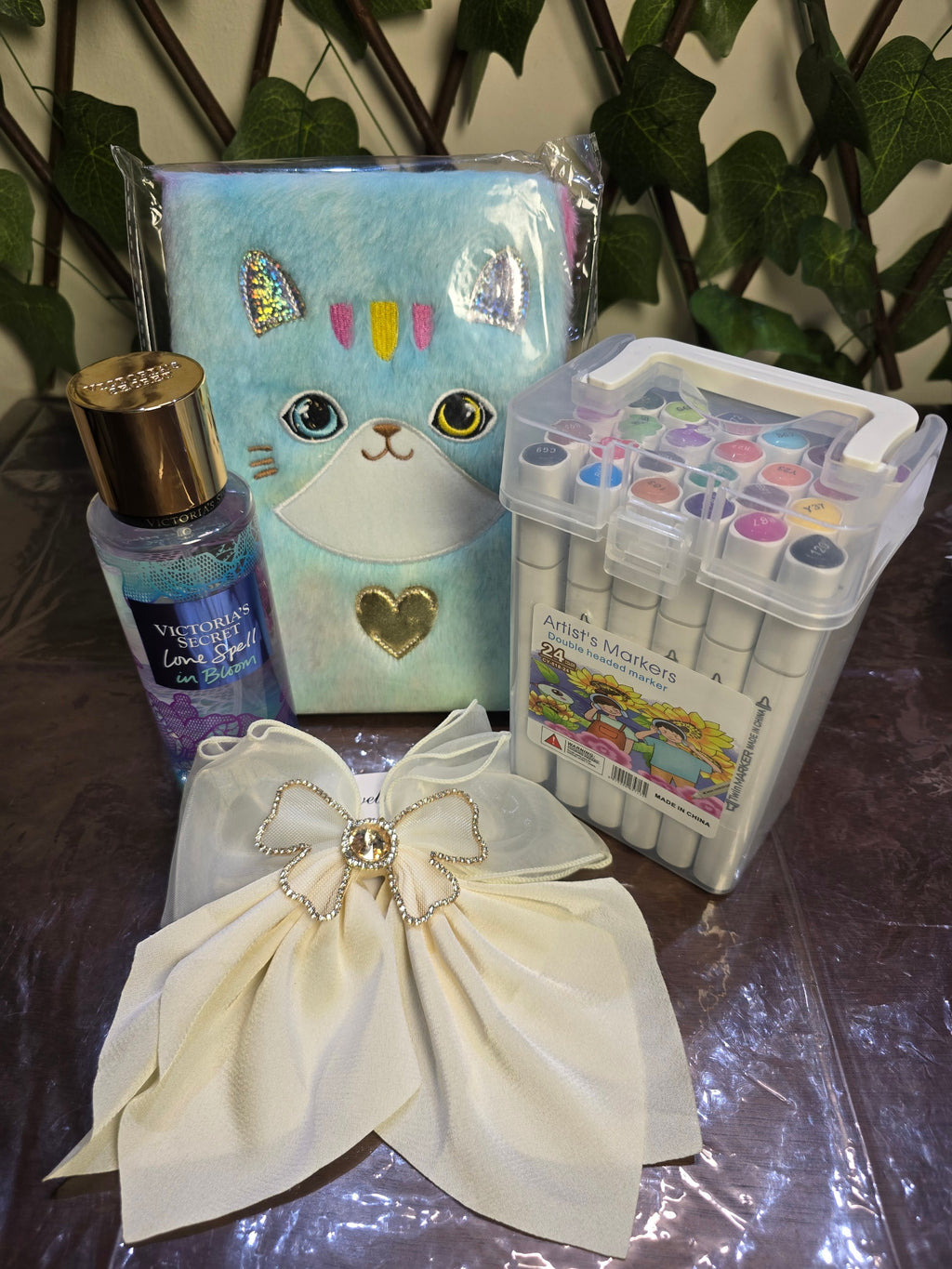 BioCode lifestyle collection featuring a blue plush cat notebook, 24 artist markers, fragrance mist, and a cream bow.