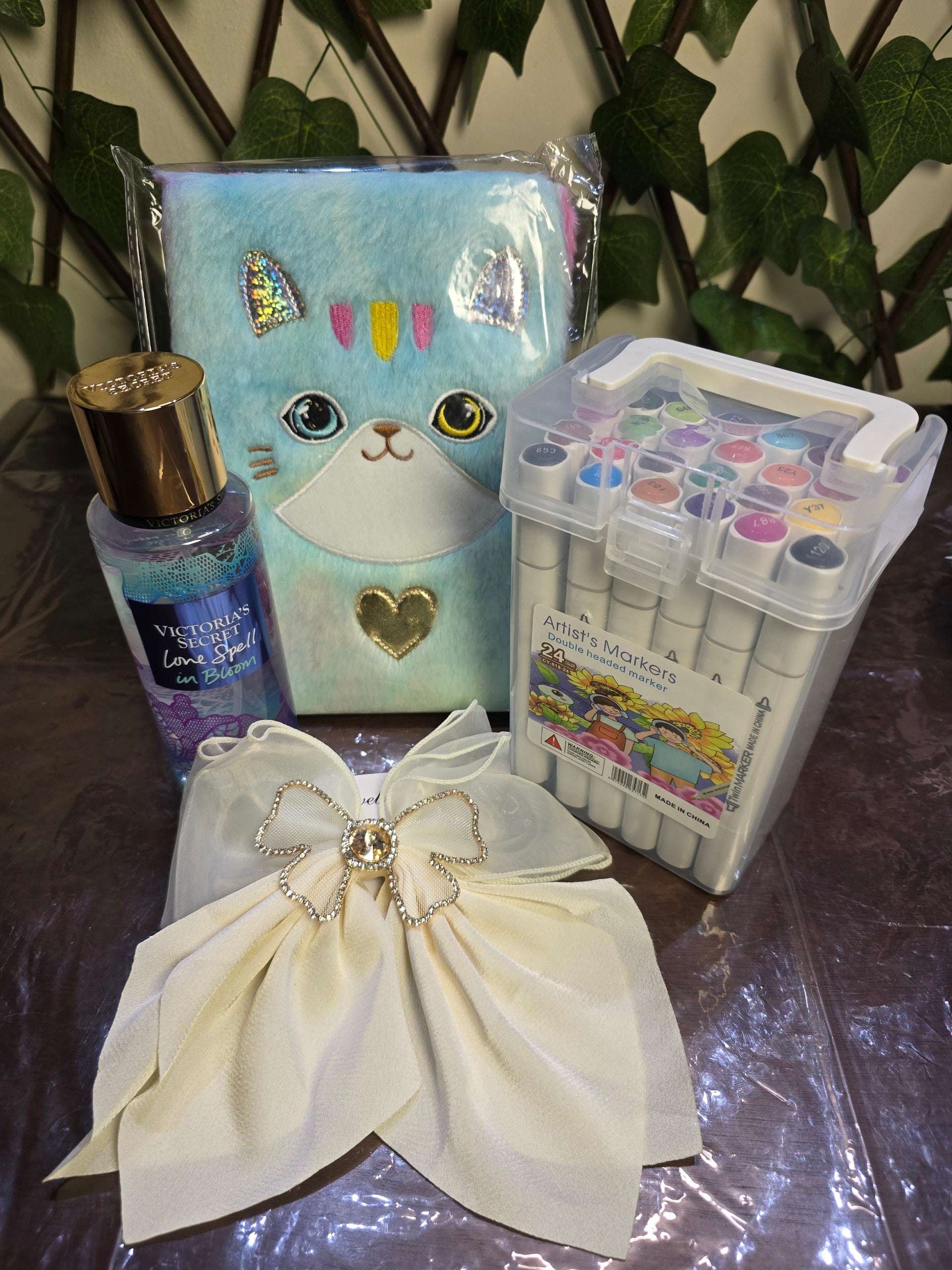 BioCode lifestyle collection featuring a blue plush cat notebook, 24 artist markers, fragrance mist, and a cream bow.